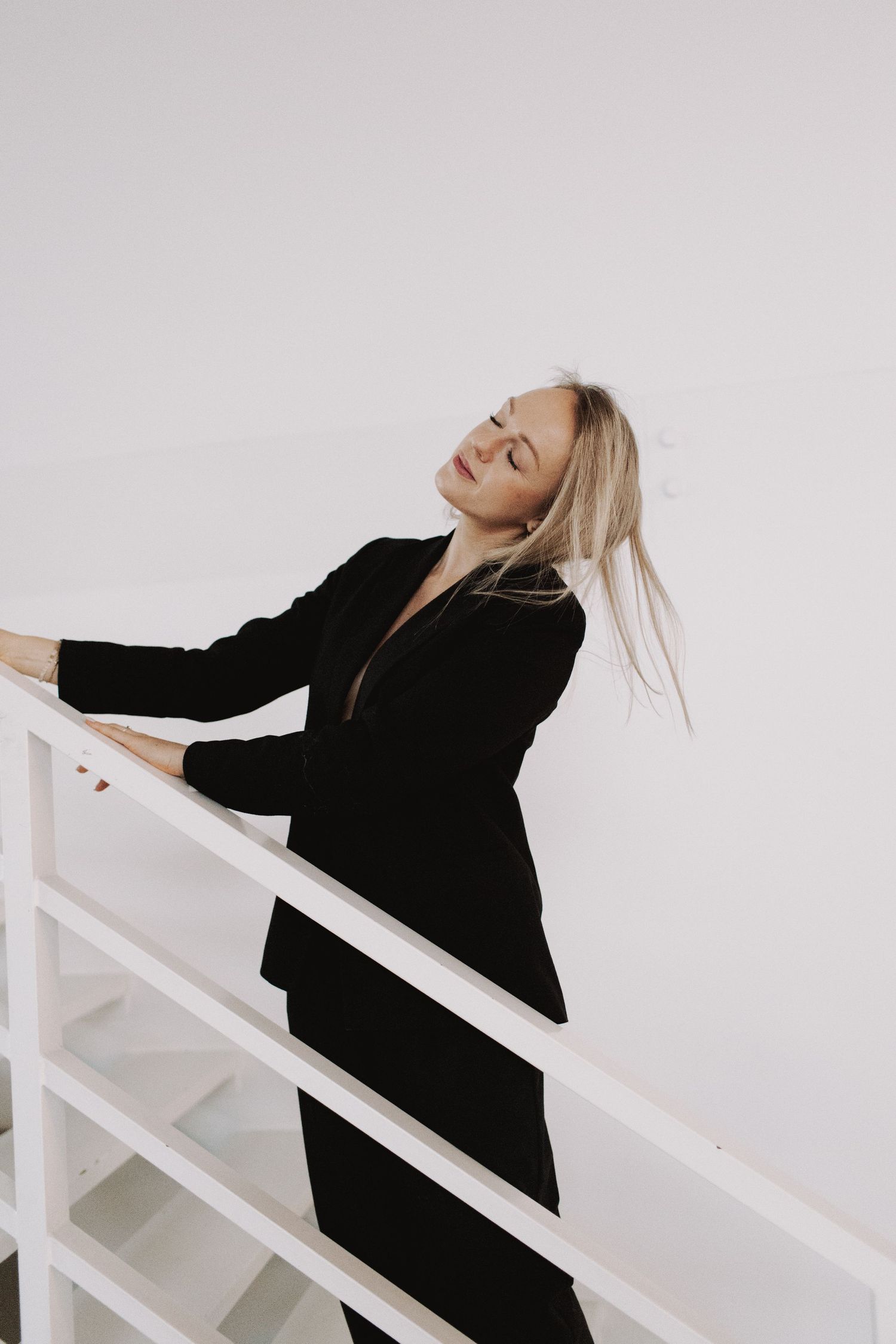 Woman in black blazer posing dramatically against white railings in artistic photo sequence.