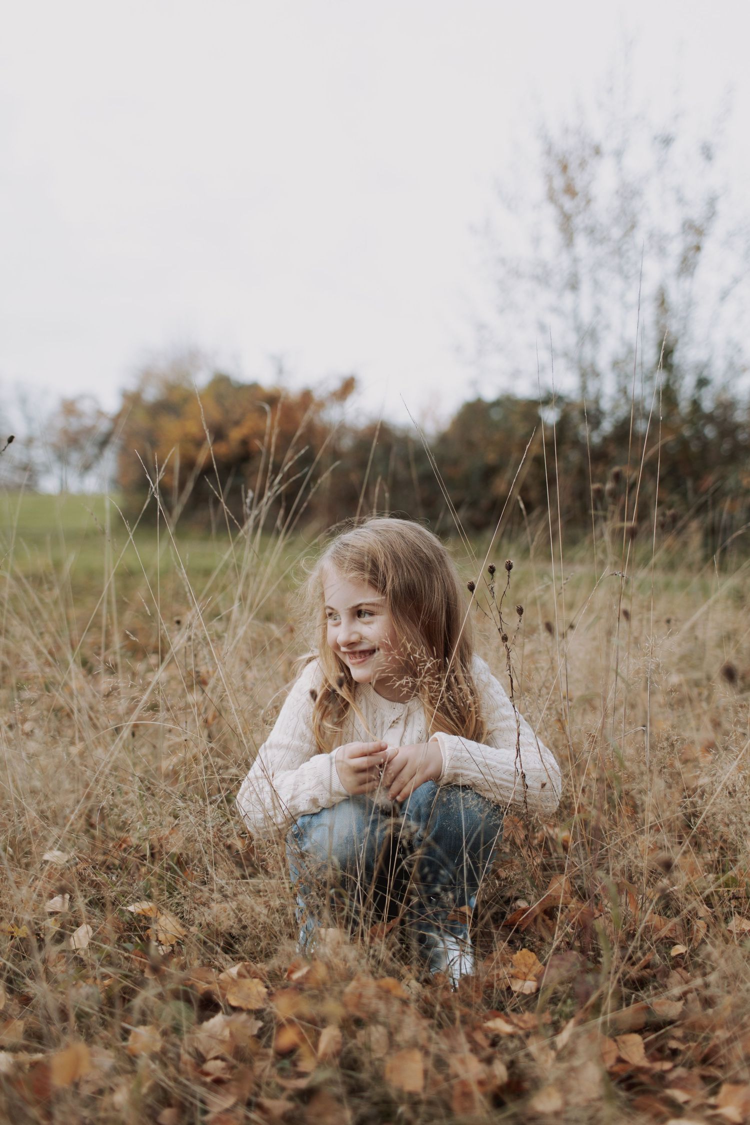 A series of candid photos showing a person sitting and laughing in a field of tall autumn grass and dried plants.