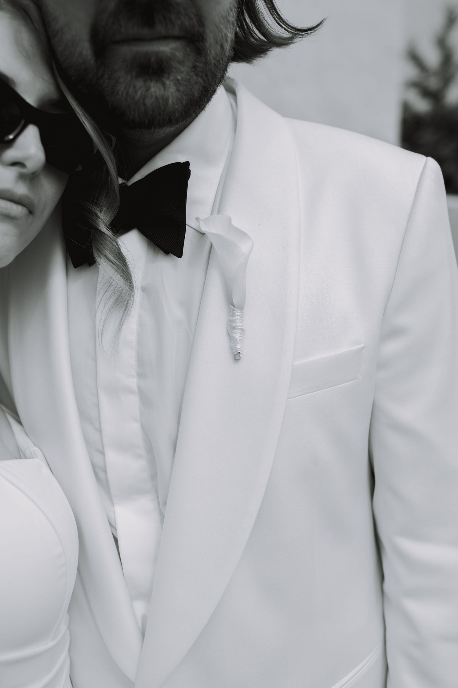 Close-up details of white tuxedo jacket and black bow tie.