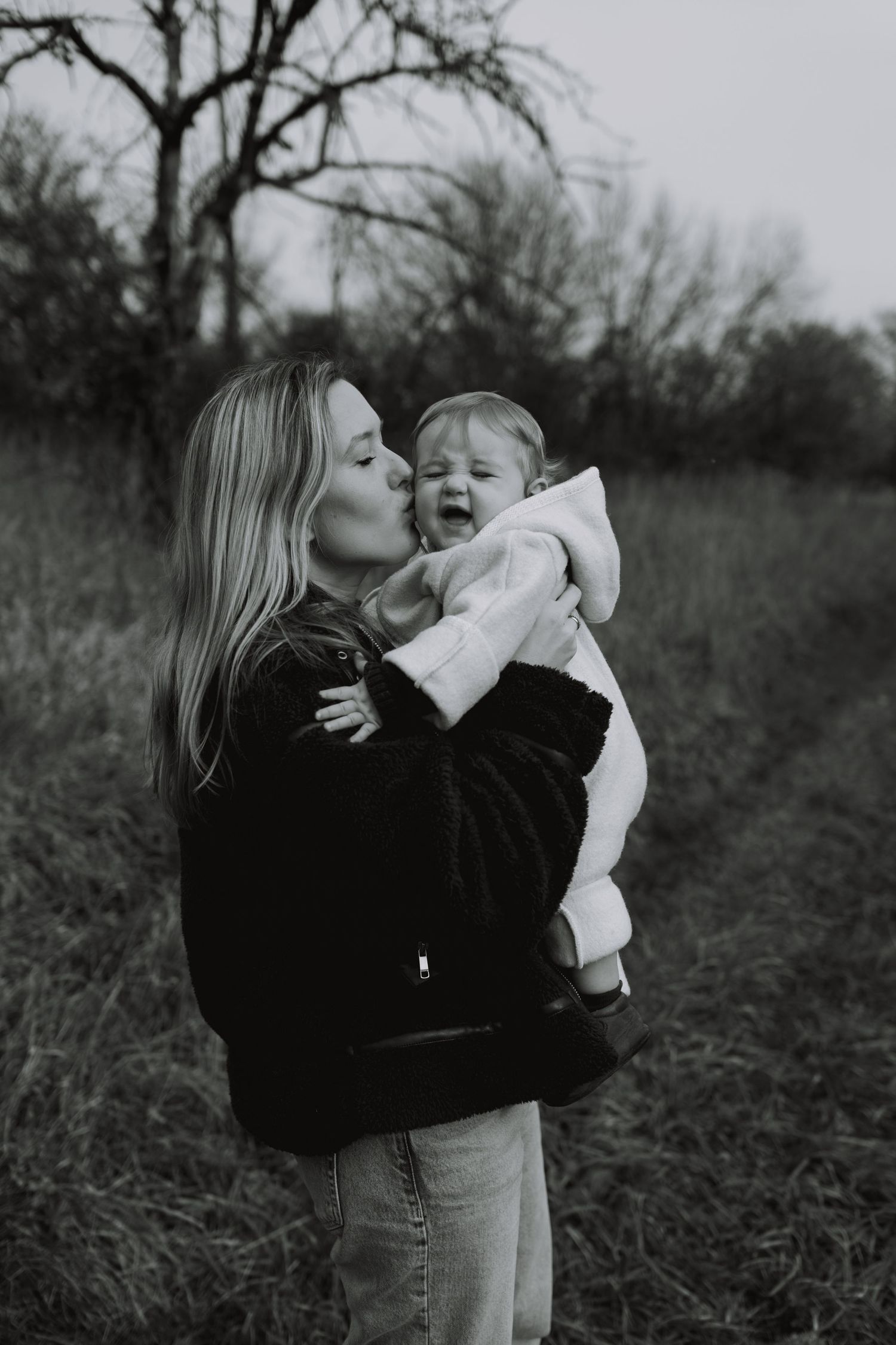 Black and white photos show tender moments between parent and child in a natural outdoor setting.