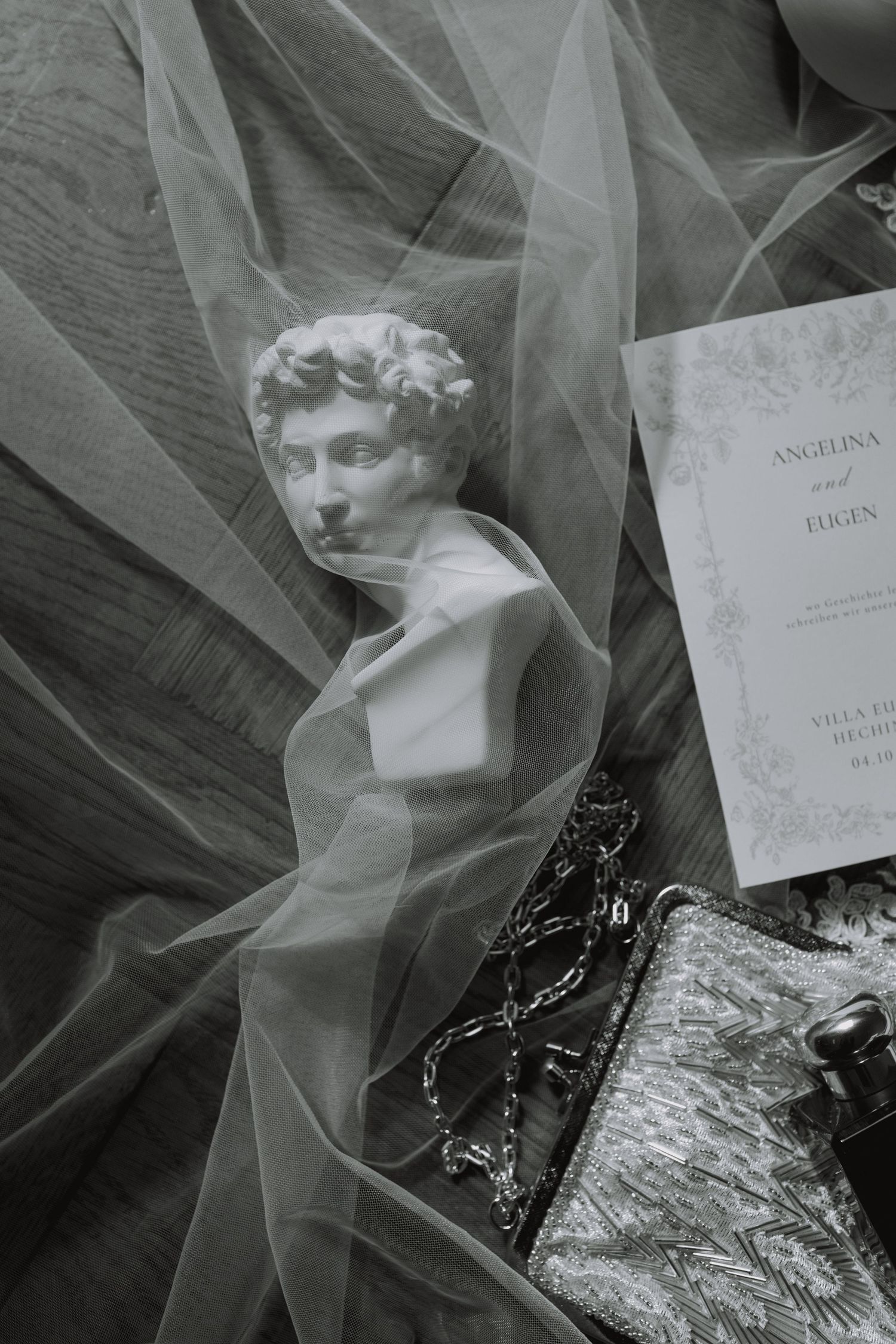 Wedding invitation and veil arranged in artistic black and white composition.