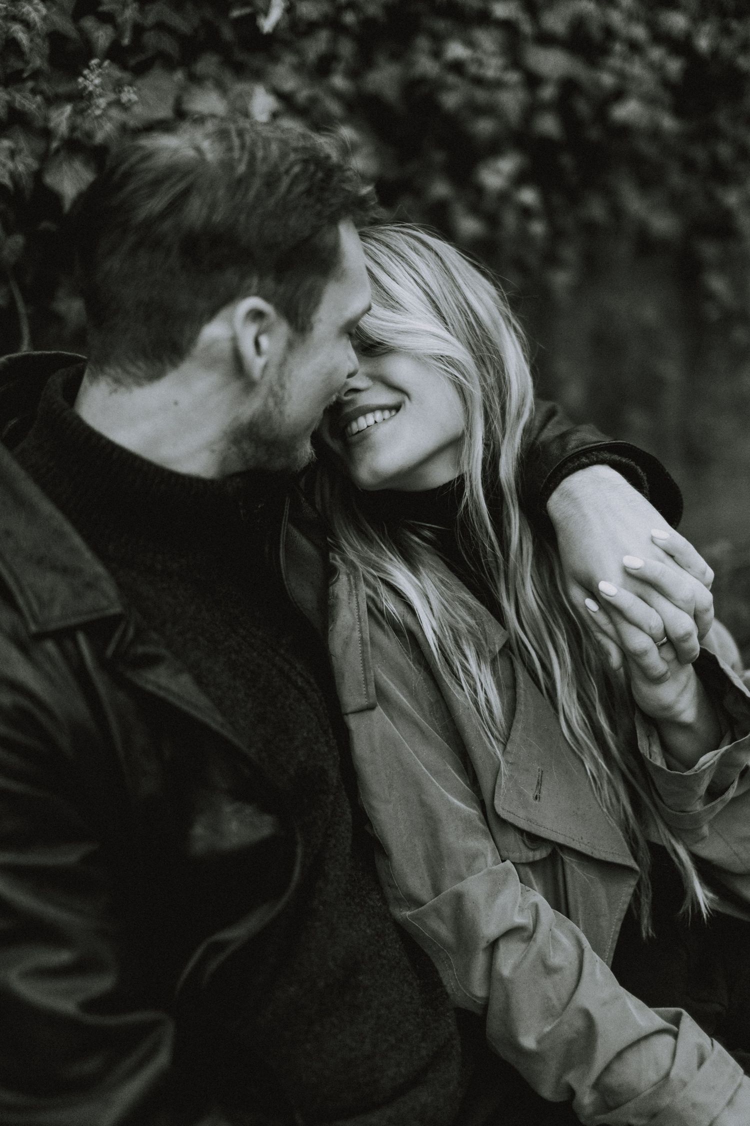 Black and white intimate portrait of a couple sharing a joyful laughing moment together outdoors.