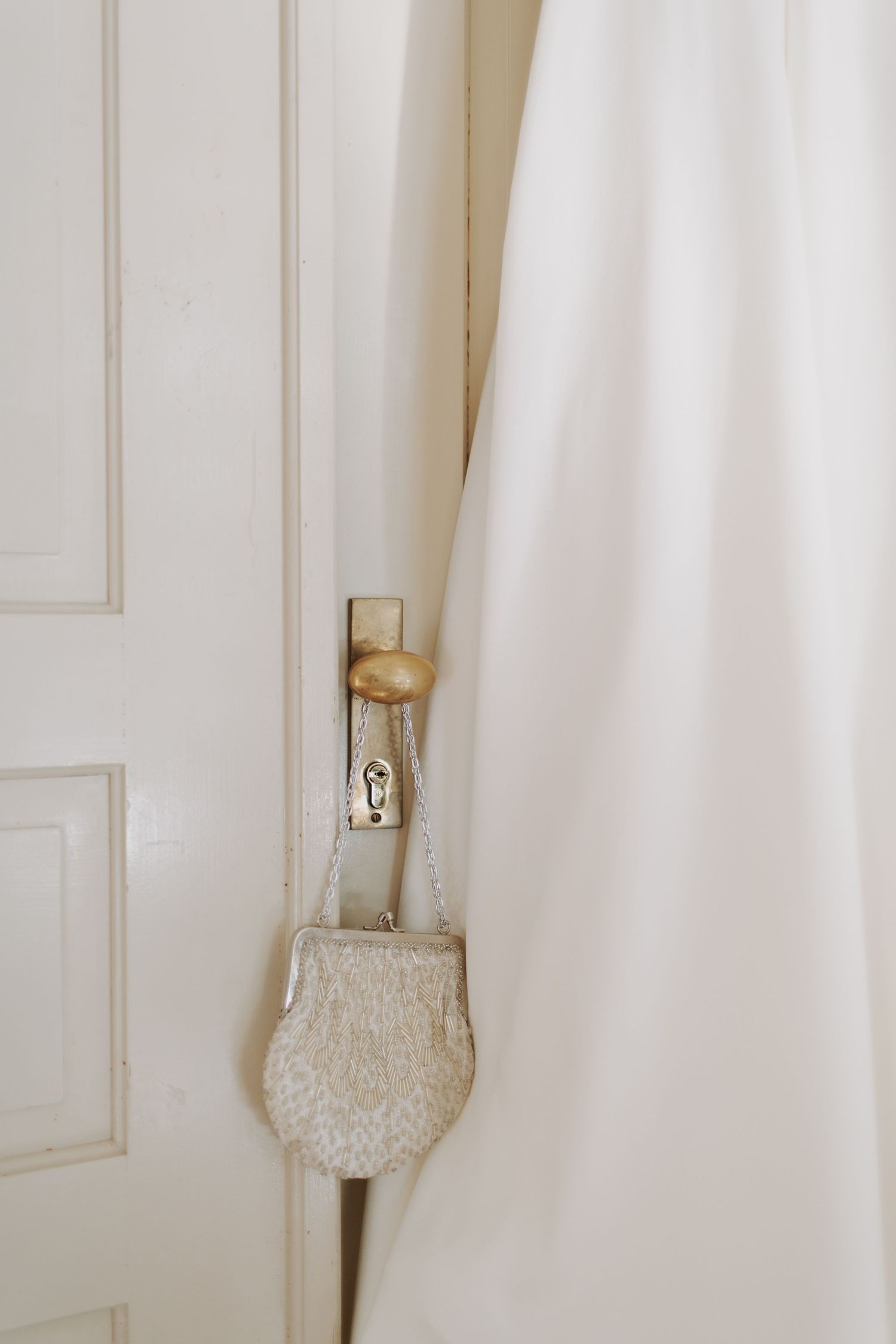White wedding dress hanging on a vintage door with ornate details.