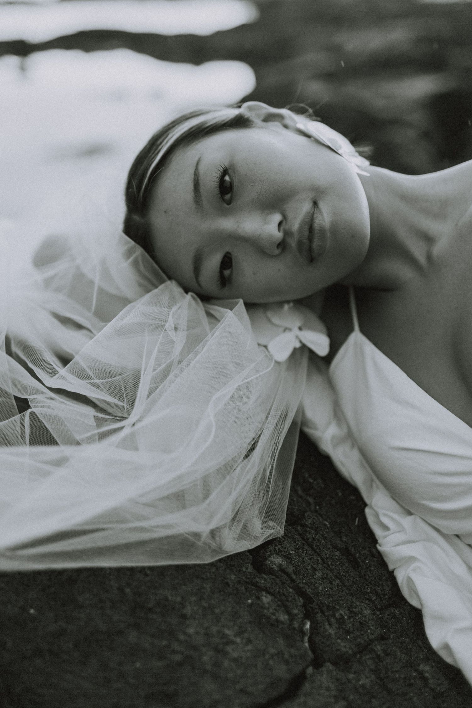 Artistic black and white portrait series featuring ethereal white tulle fabric against a dark background.