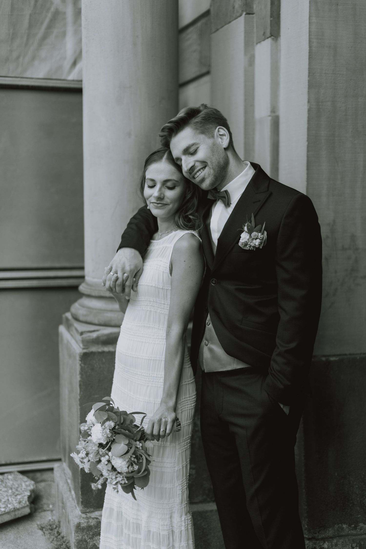 Black and white wedding photo series showing romantic moments between couple with columns in the background.