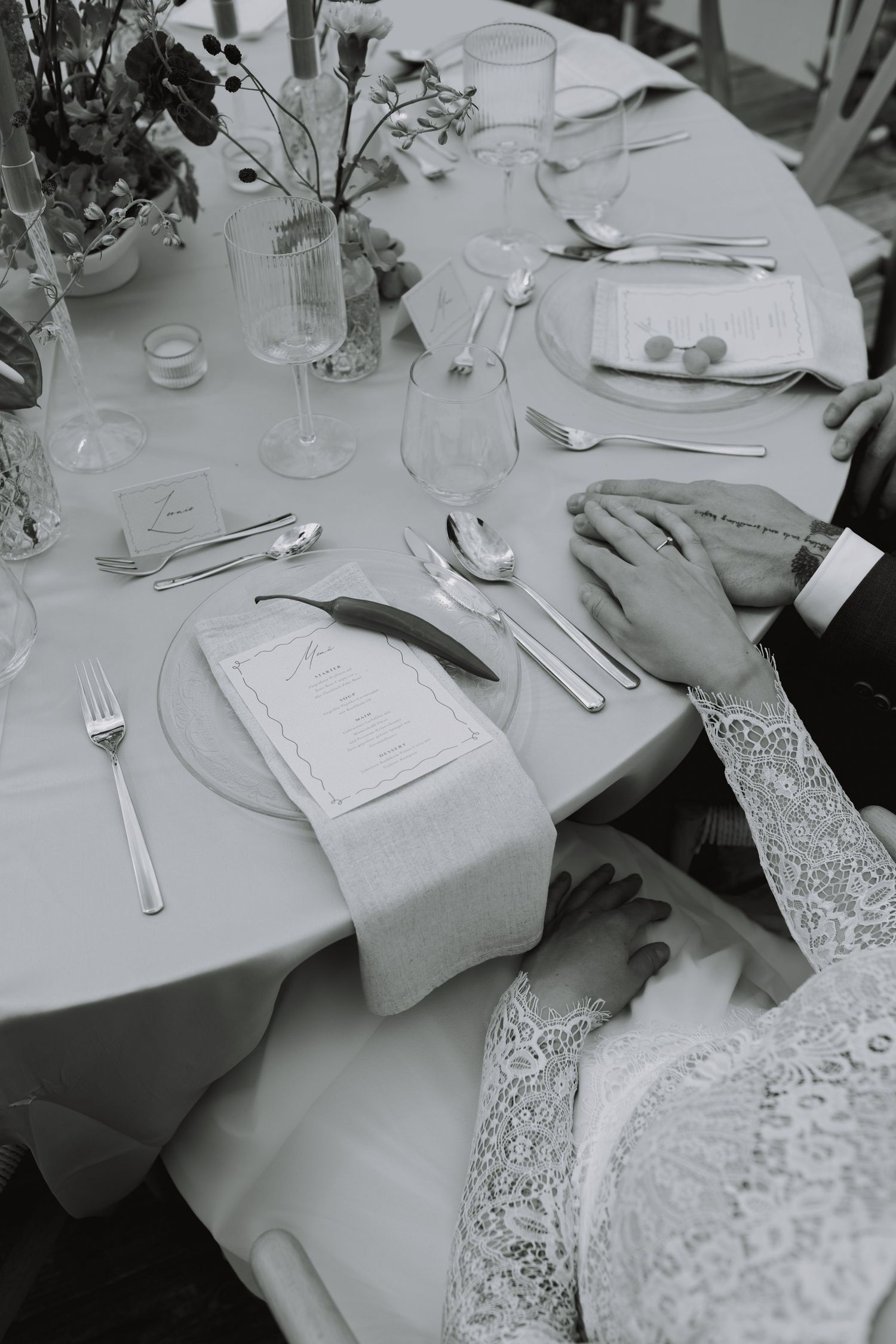 Elegant white table settings with lace tablecloths and formal silverware arranged for a formal dining event.