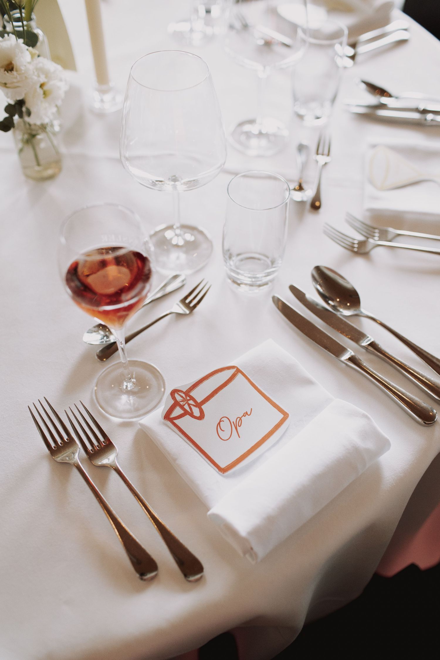 Elegant wedding reception table setting with white linens and place cards.