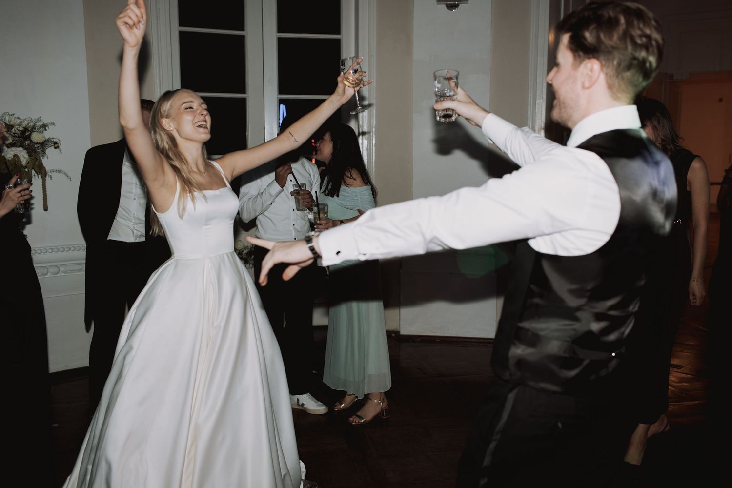 Wedding celebration with guests dancing and twirling in formal attire.