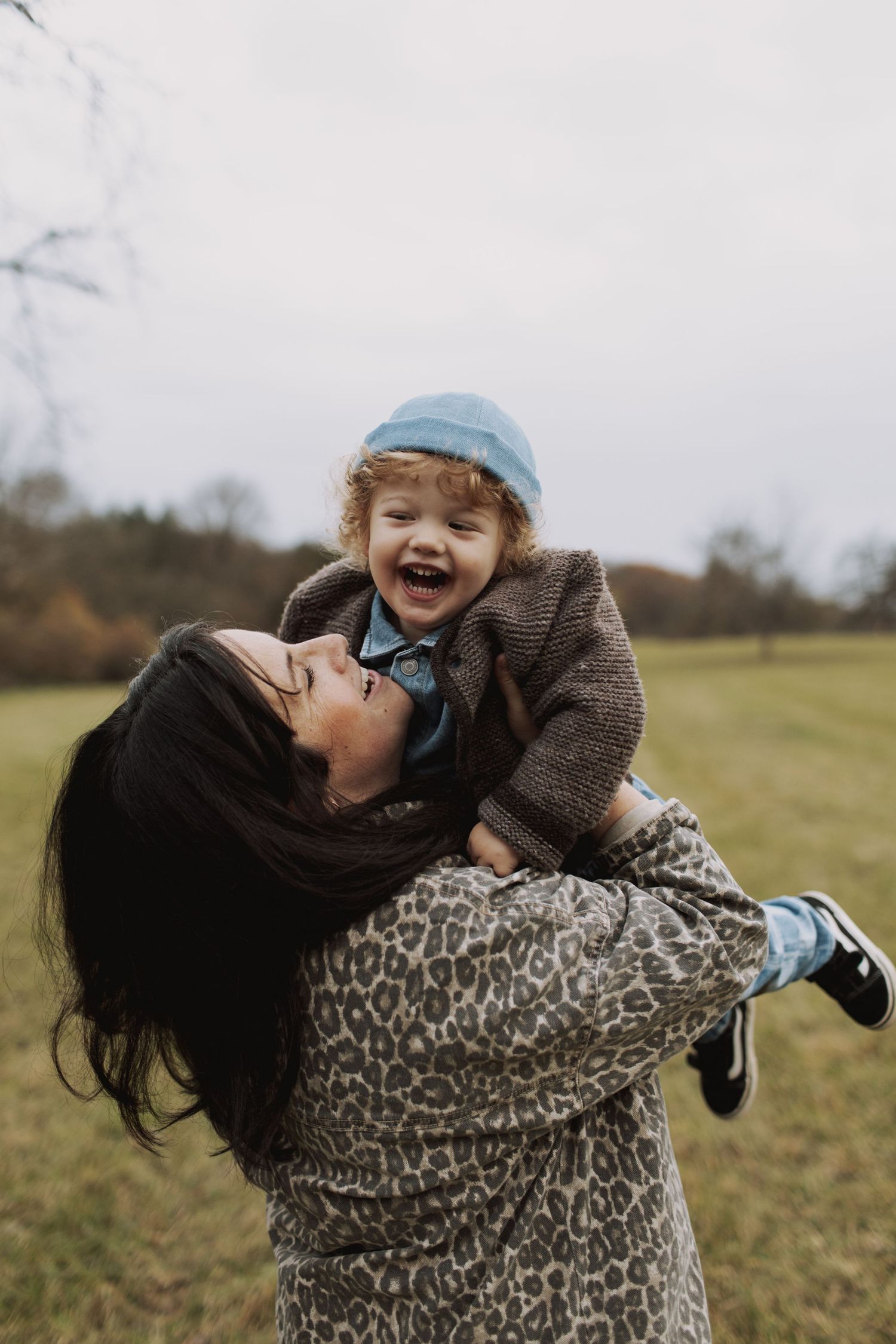 A parent and child share joyful moments while playing together in an autumn field.