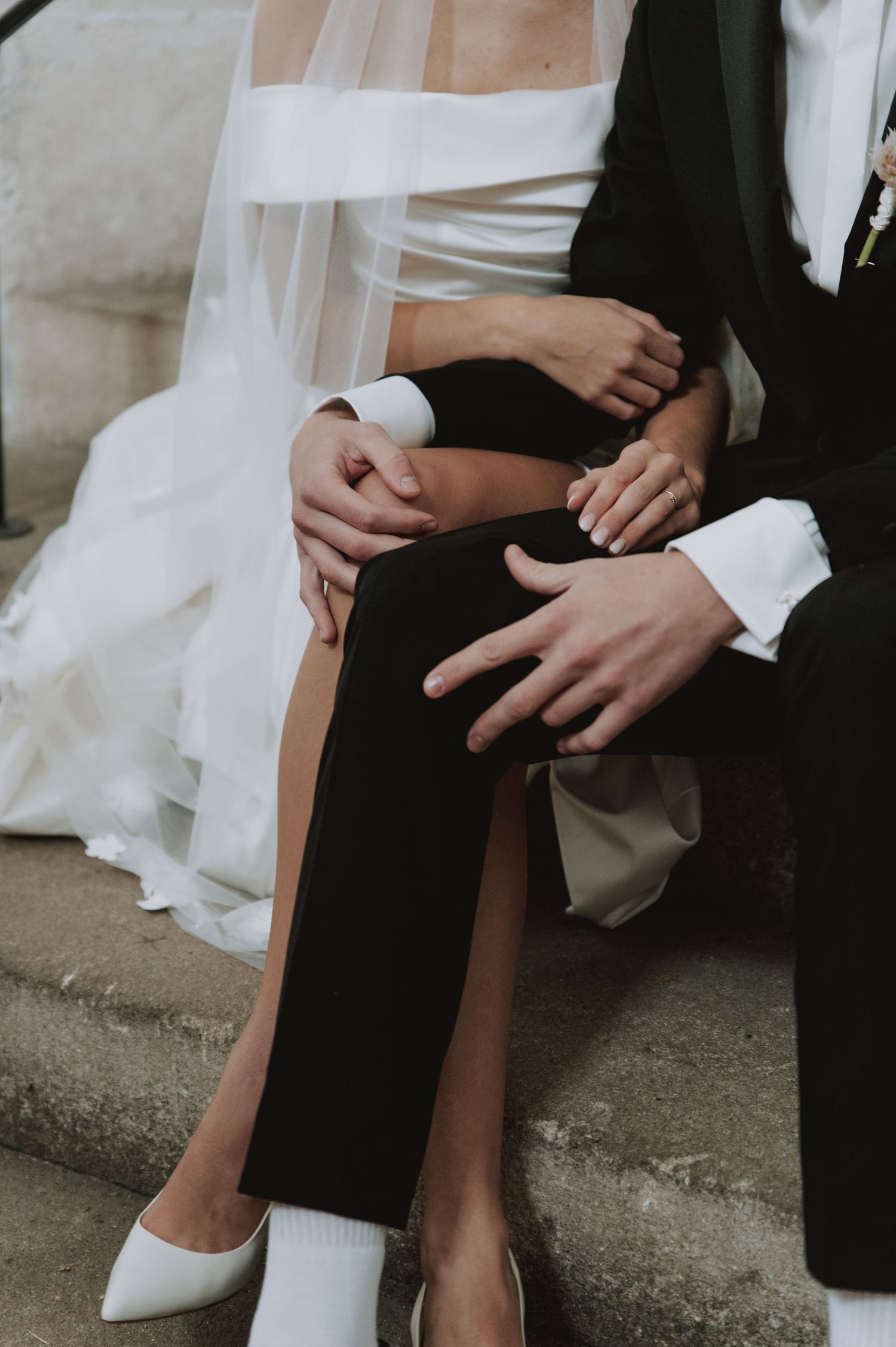 Intimate detail shot of couple sitting together showing formal wedding attire.