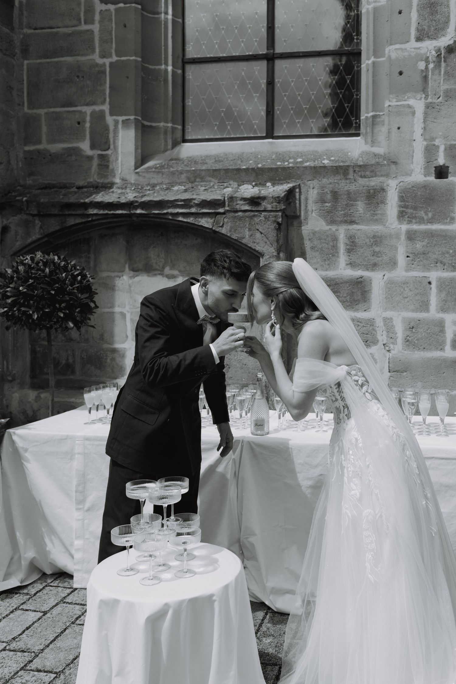A romantic black and white moment between newlyweds by a champagne tower.