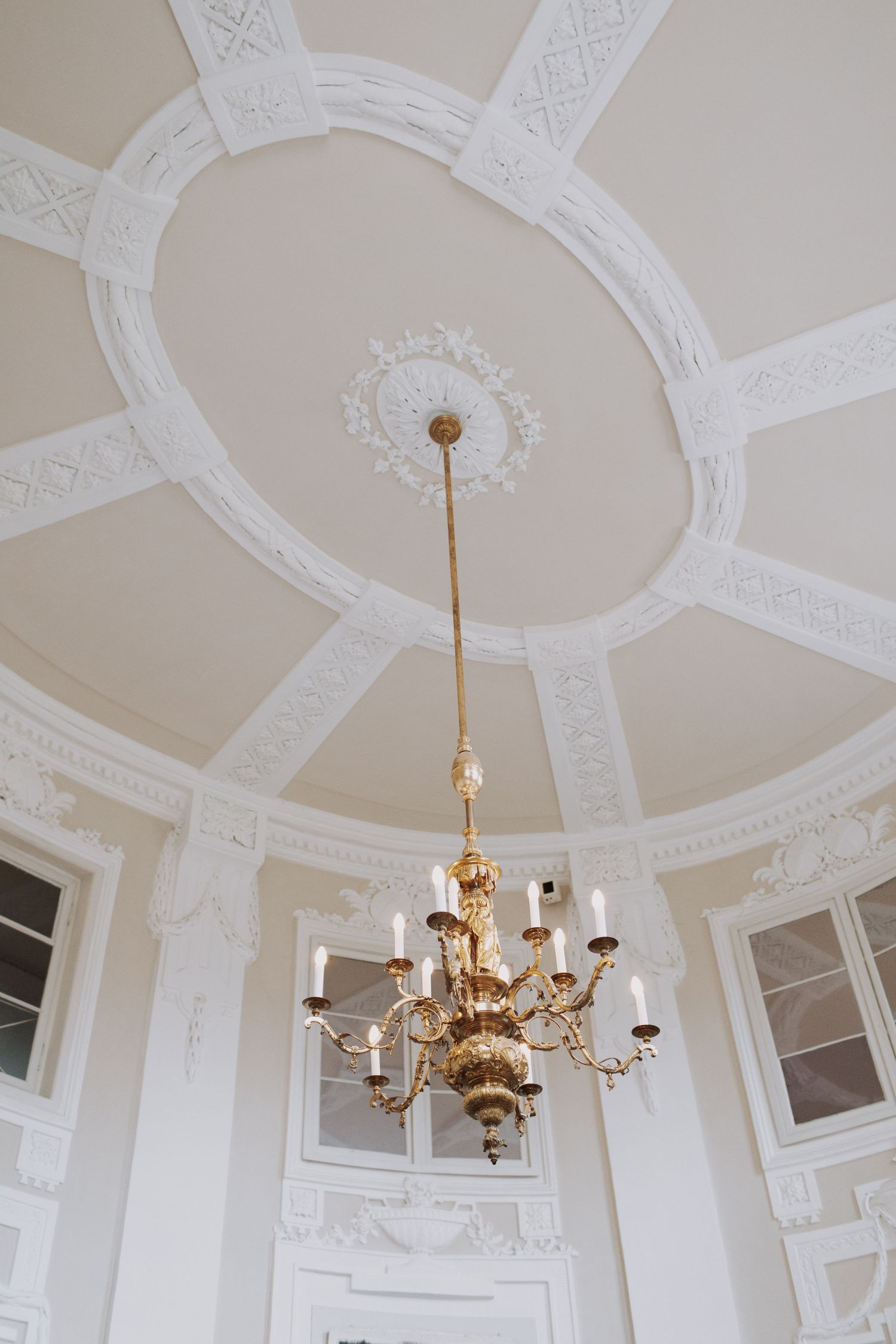 An ornate white ceiling with decorative moldings and crystal chandelier in a grand room.
