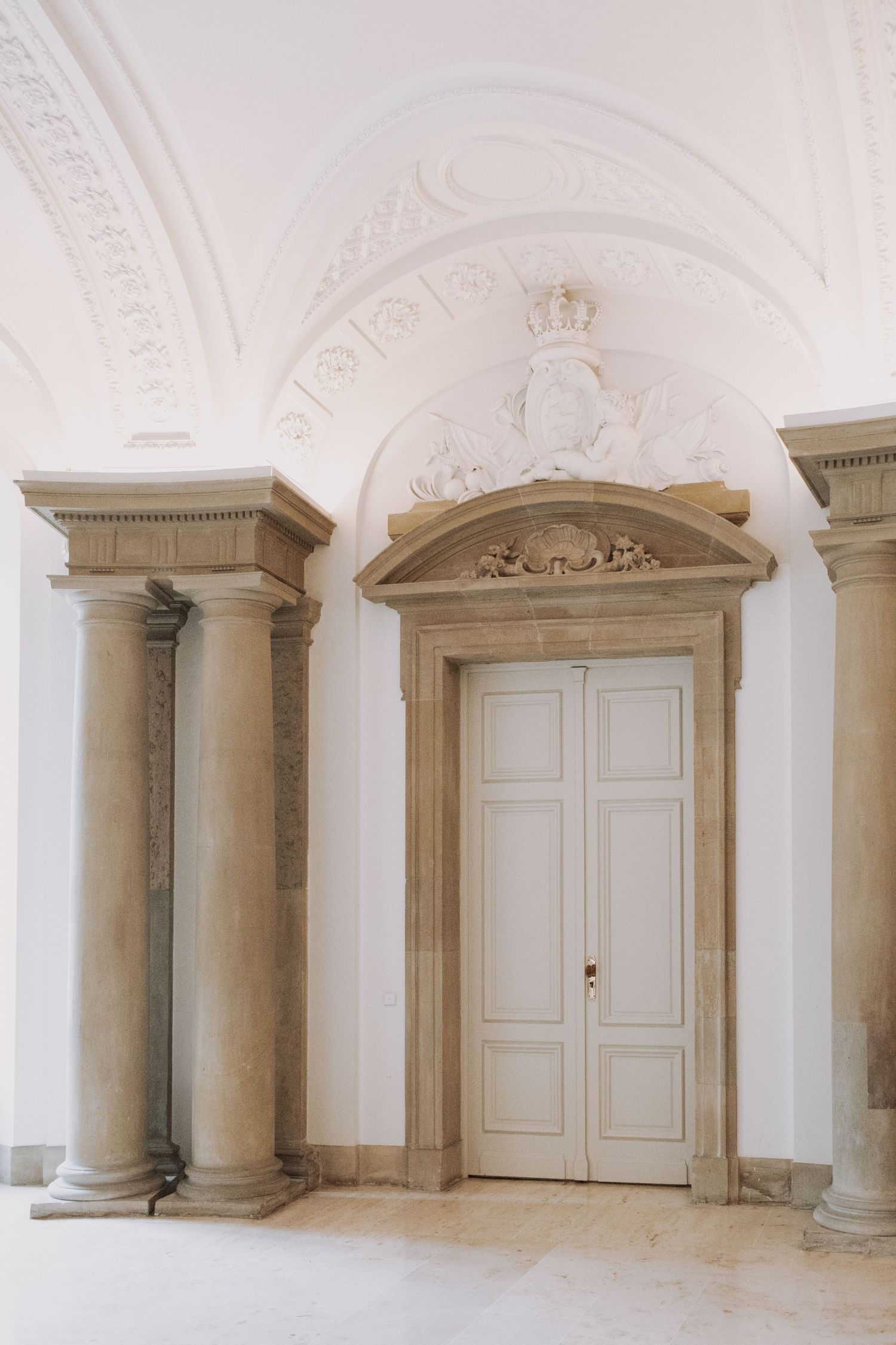 Elegant white doorway with classical columns and ornate ceiling moldings.