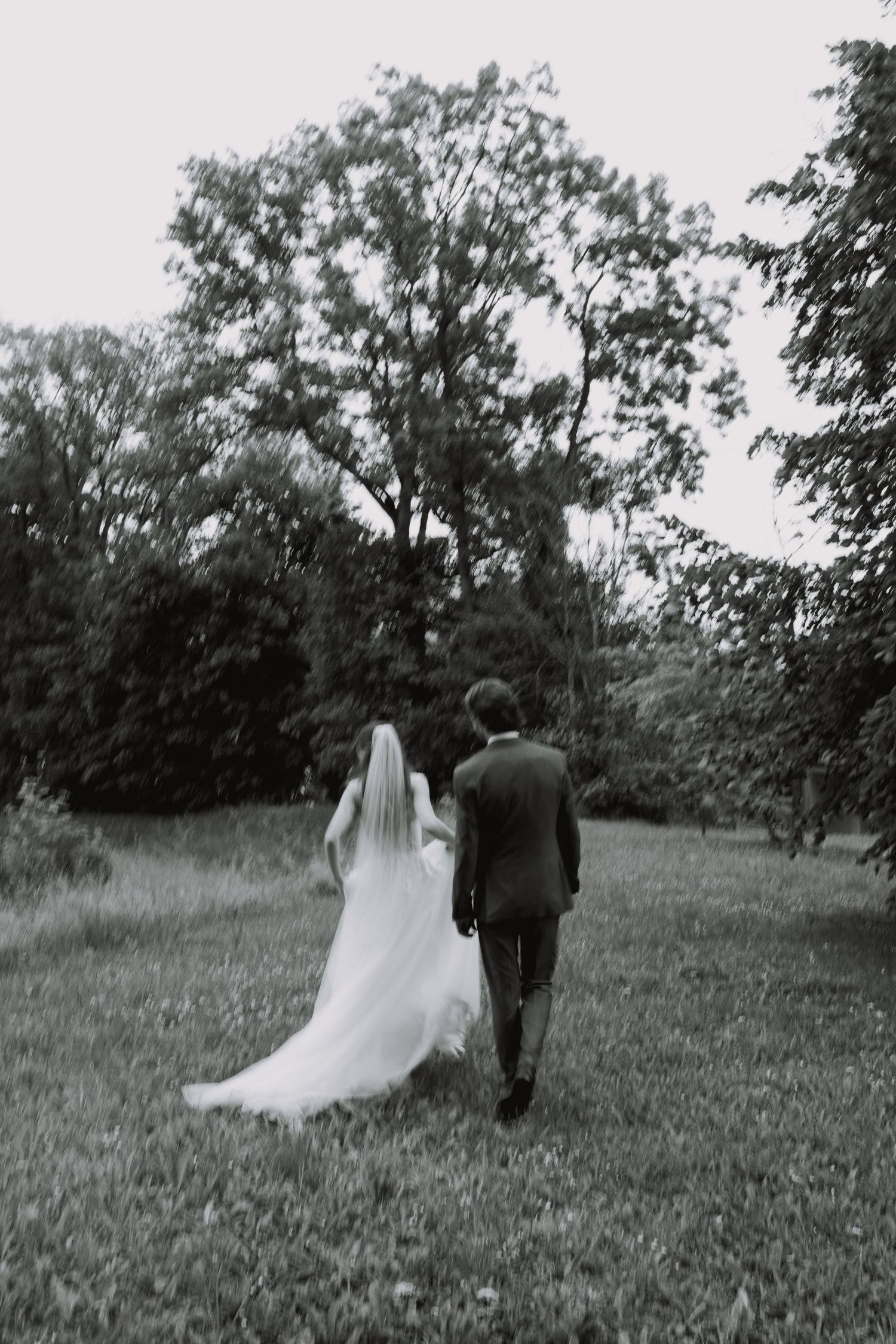 Newlyweds walking together through a lush green outdoor setting.