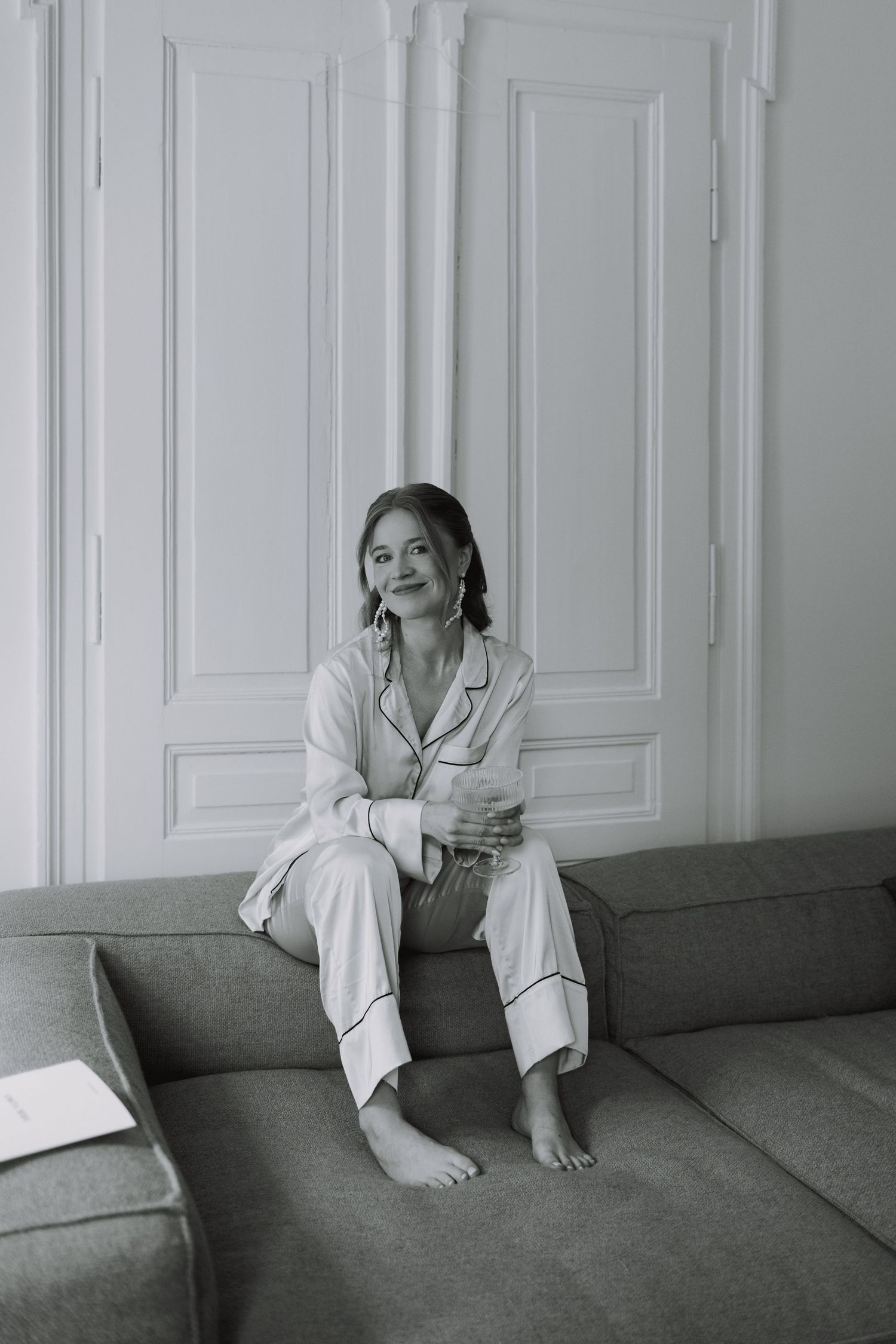 A relaxed pre-wedding moment in white pajamas on a gray couch against white paneled walls.