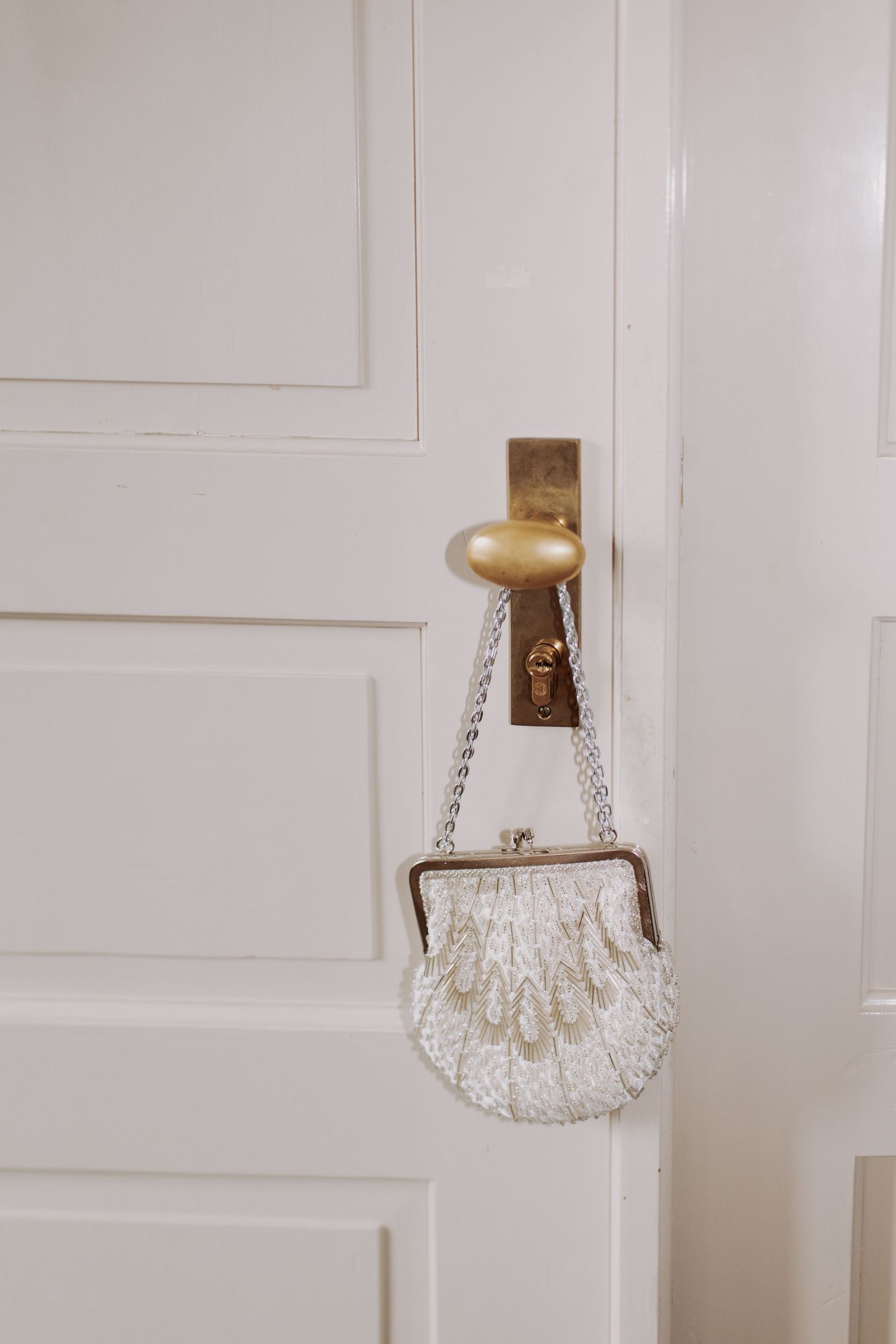 Crystal beaded purse hanging on white door handle.