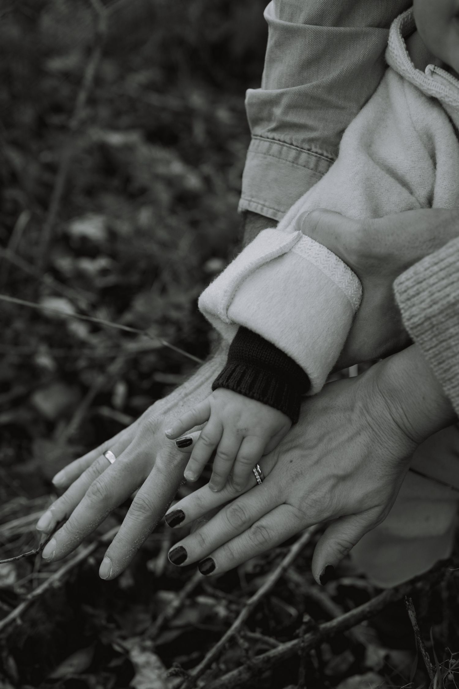 Black and white close-up sequence of hands planting seeds or seedlings in dark soil.