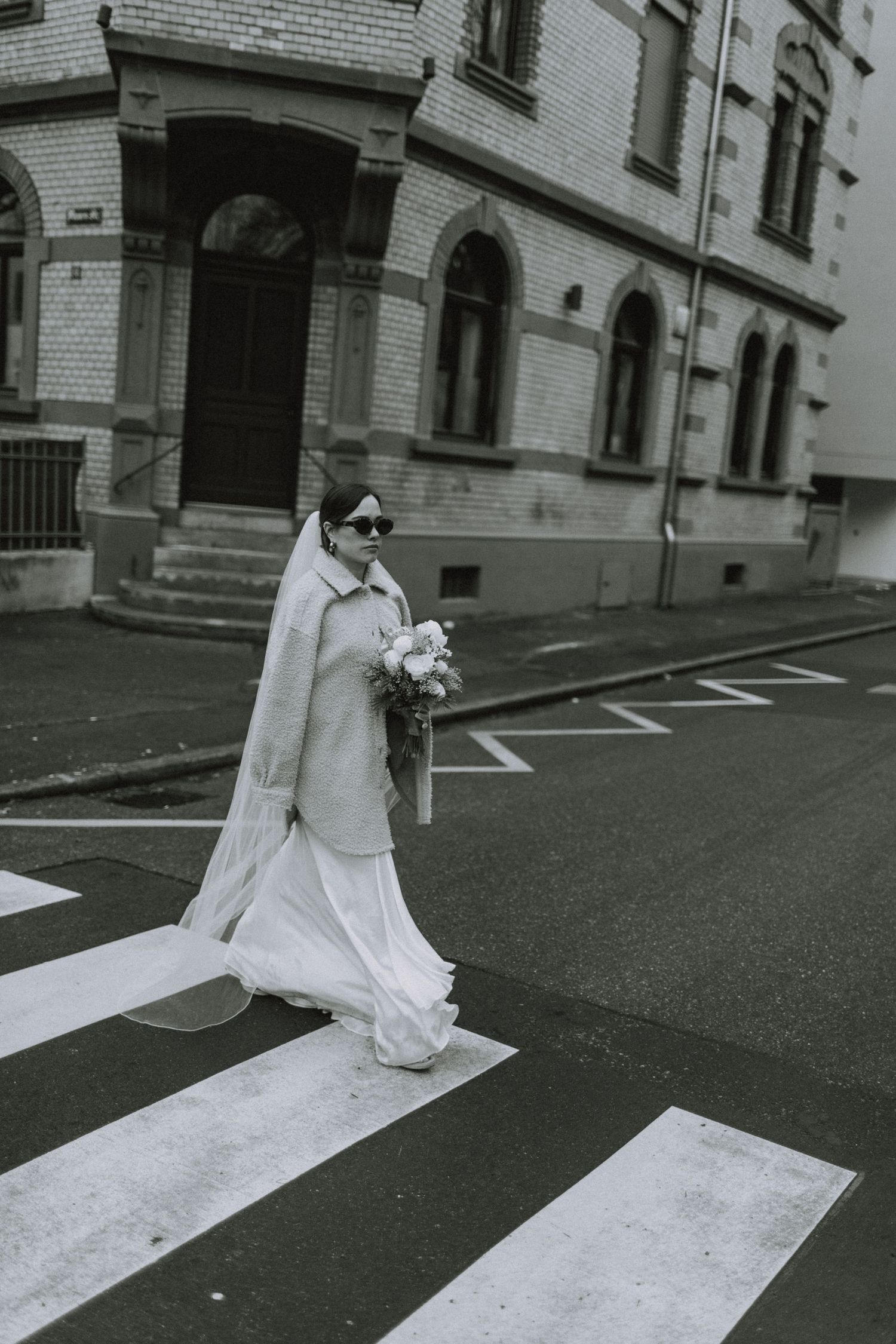 Artistic black and white street photos of person in white dress crossing painted road markings.