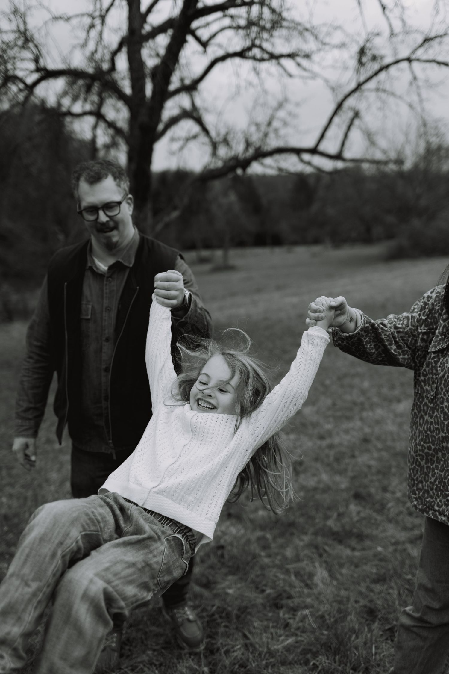 A black and white photo sequence shows a playful outdoor moment between two people in a natural setting.