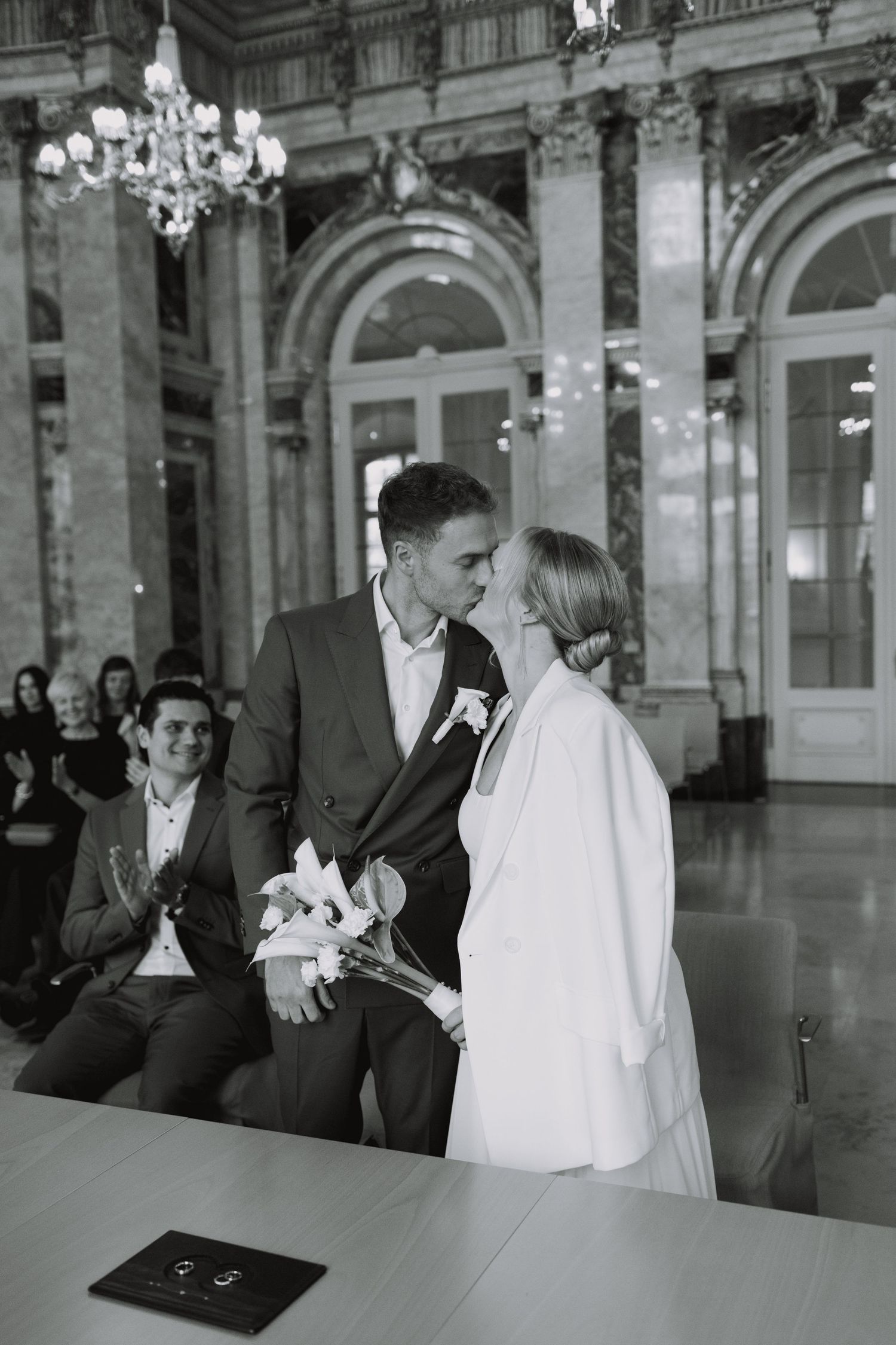 Elegant wedding ceremony in grand historic building with ornate architecture and chandelier.