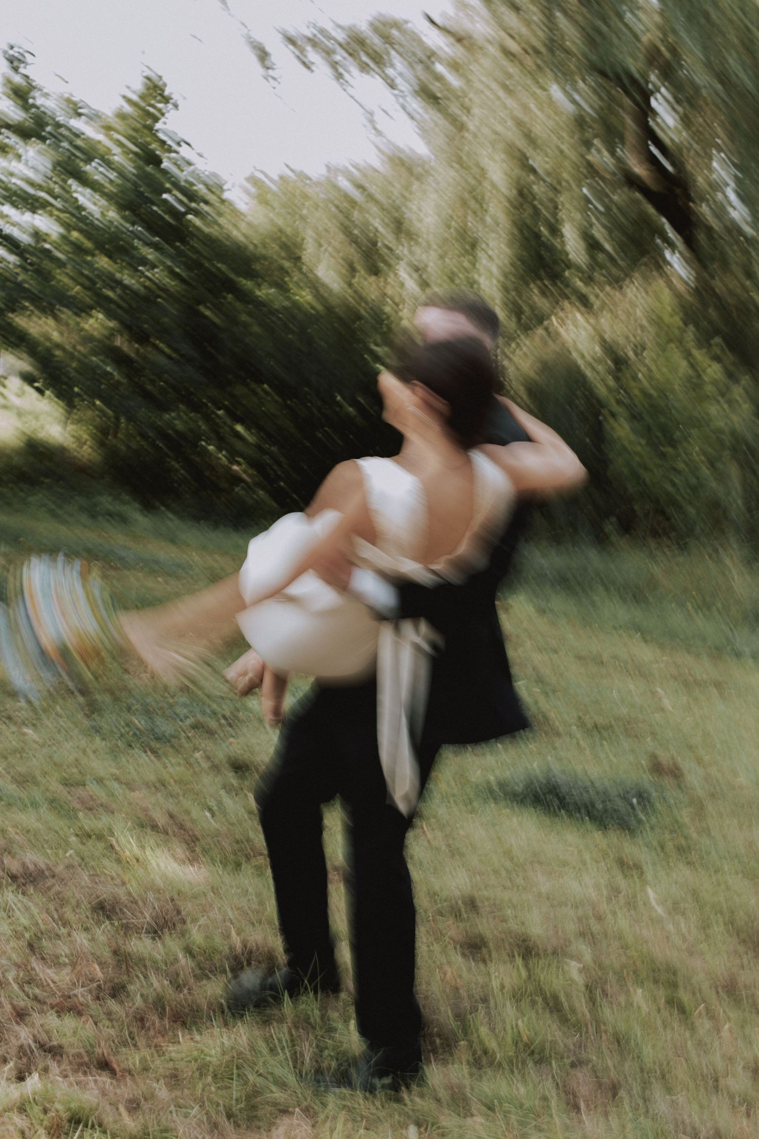 Couple spinning and dancing together in a grassy outdoor setting with motion blur effect.