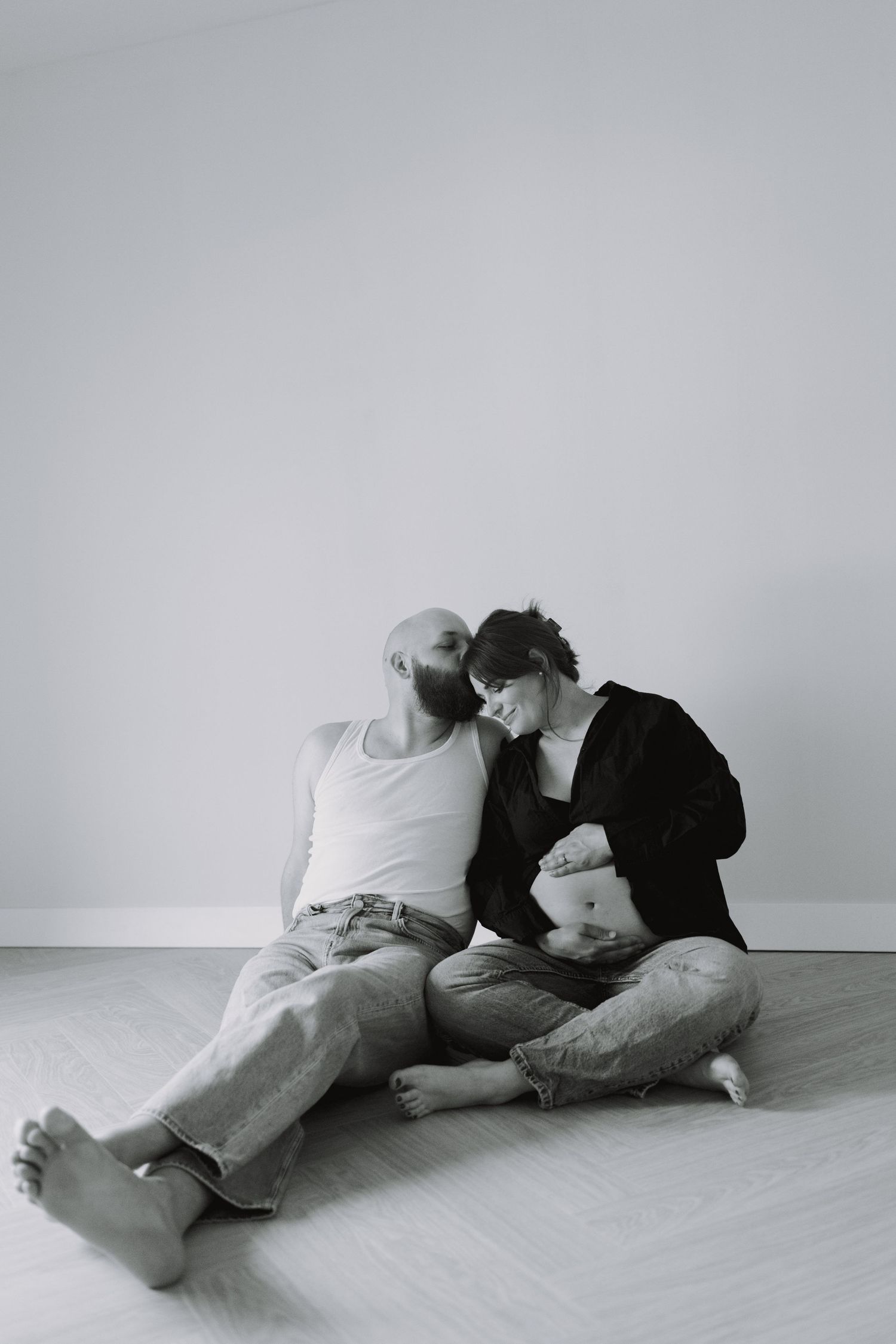 Series of intimate black and white photos showing two people lying close together on a light floor.