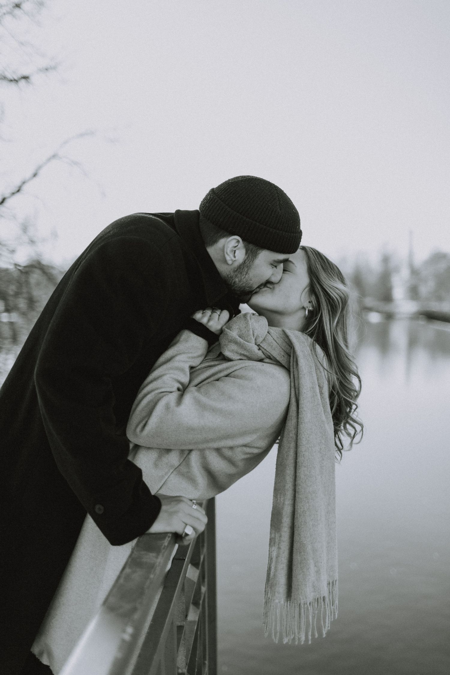 A romantic black and white photo of a couple sharing an intimate moment by a lake.