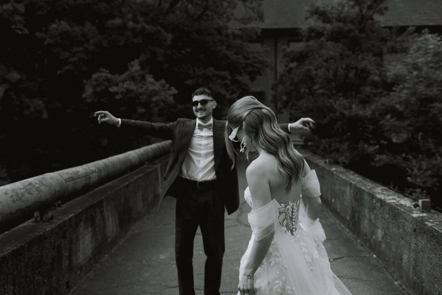 A wedding couple walking together on a stone pathway surrounded by greenery.