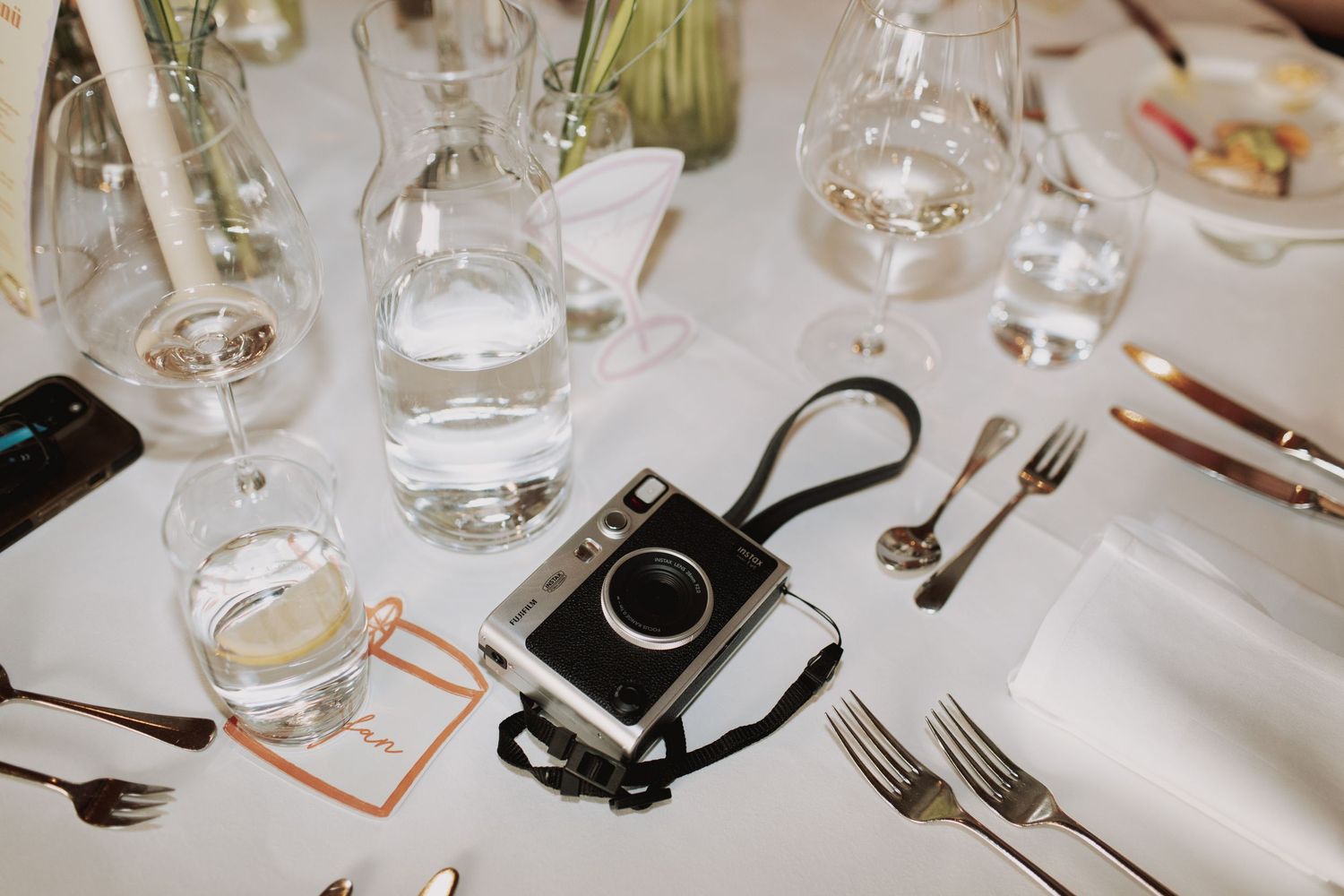 Wedding reception table settings with glassware and place cards.