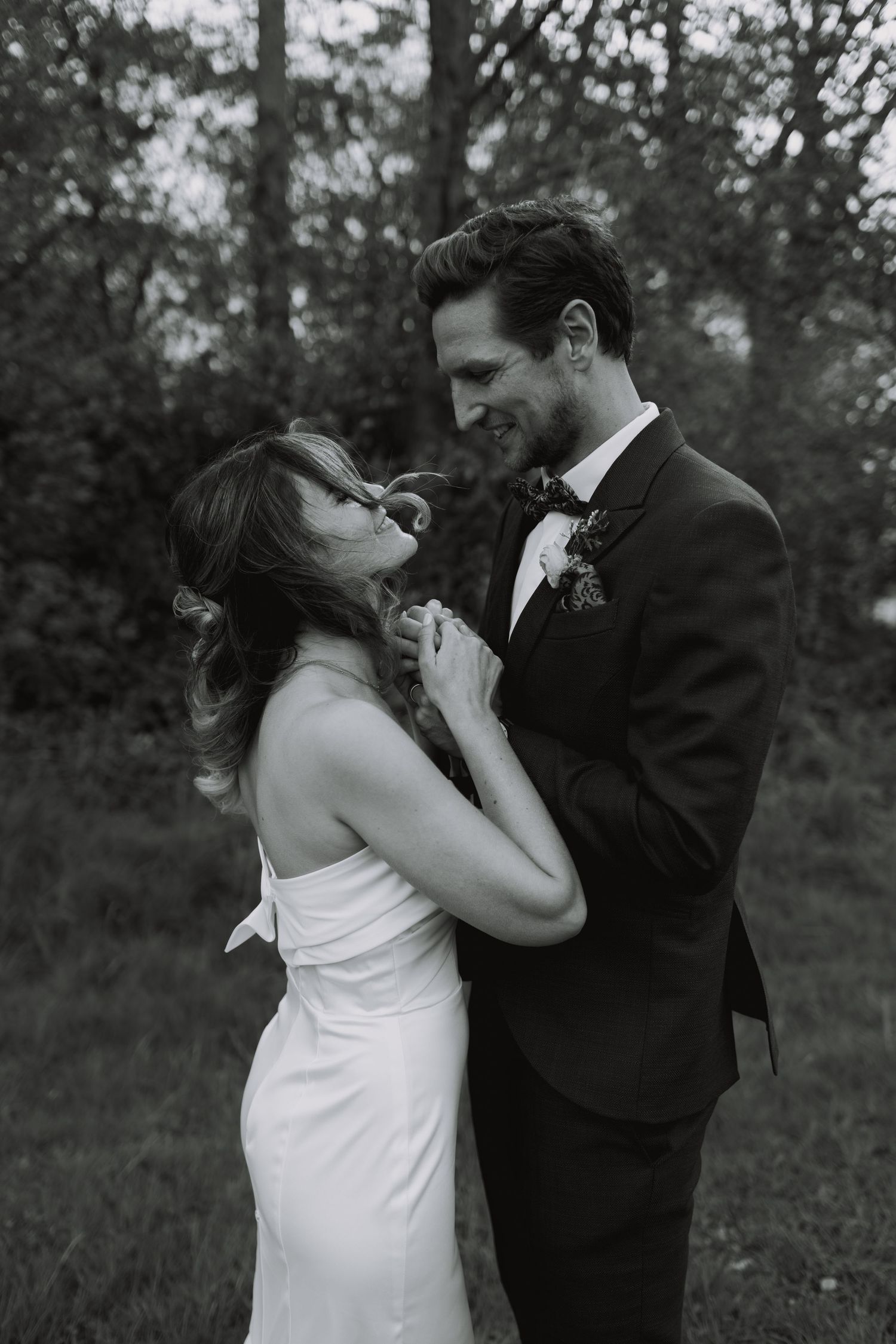 Romantic wedding couple sharing a playful moment with champagne glasses in a garden setting.