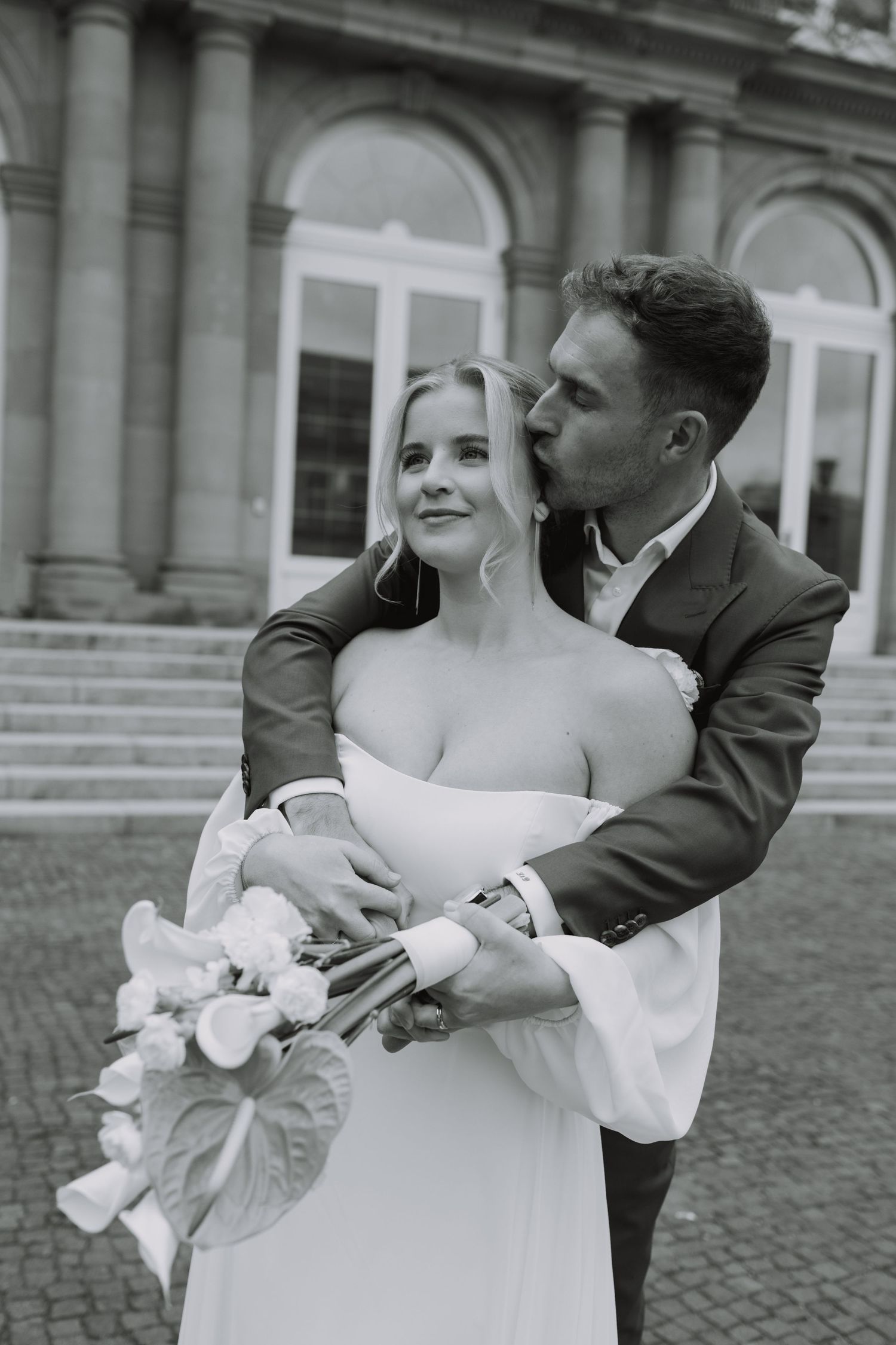 A romantic black and white photo sequence shows a couple dancing and embracing outside a grand building.