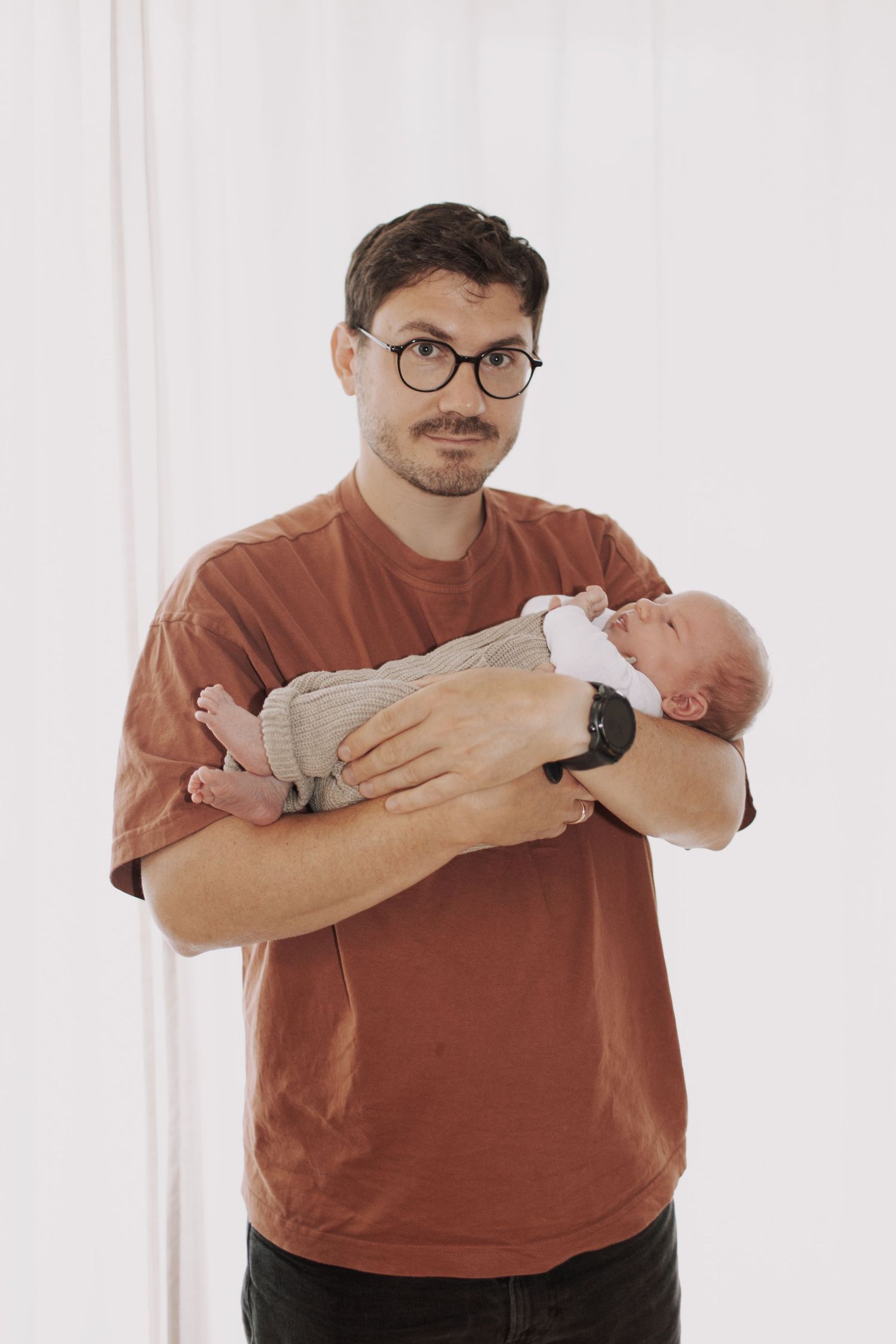 Series showing someone in a rust-colored shirt holding and cradling a small baby.