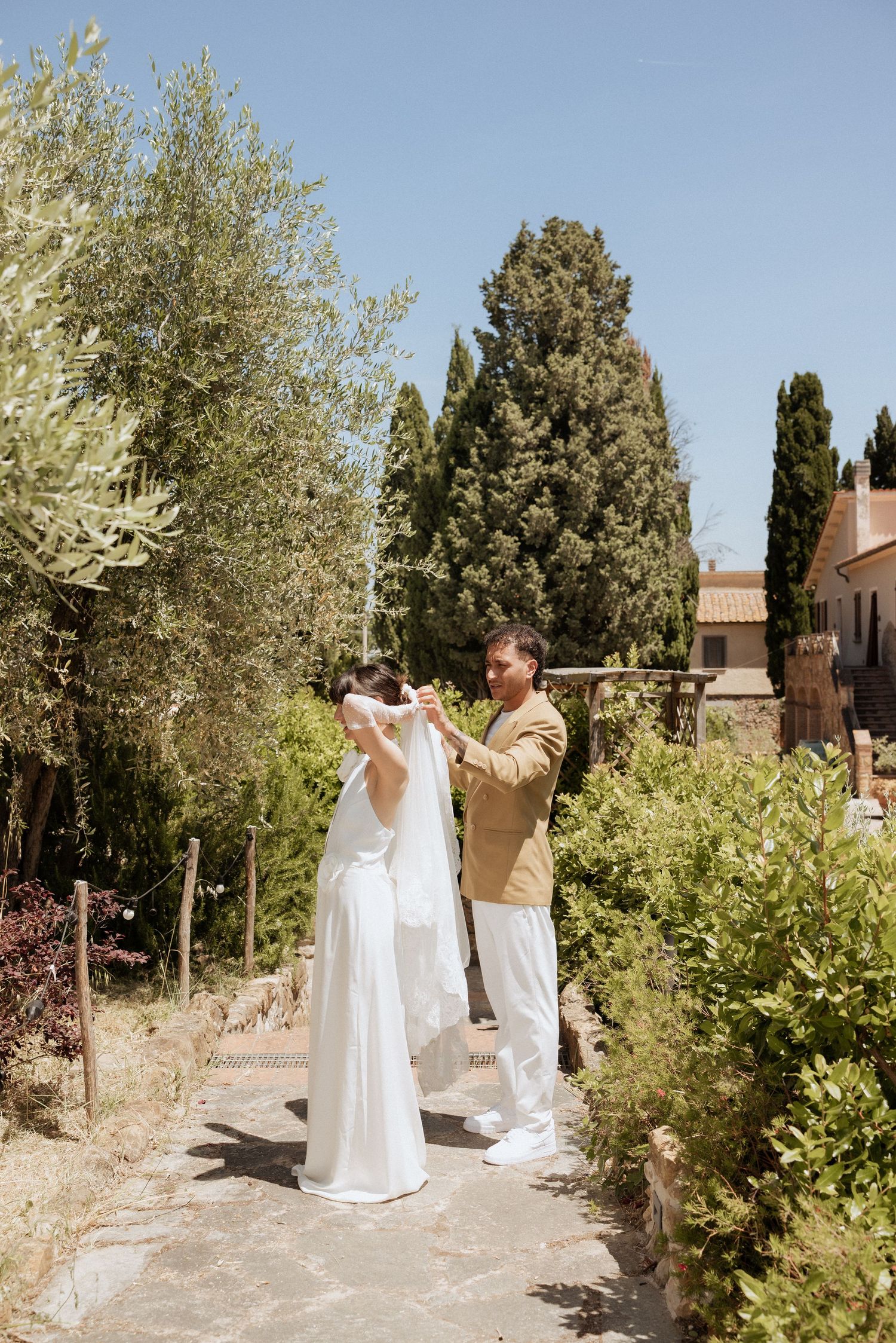 Groom helping bride with the veil in Tuscany.
