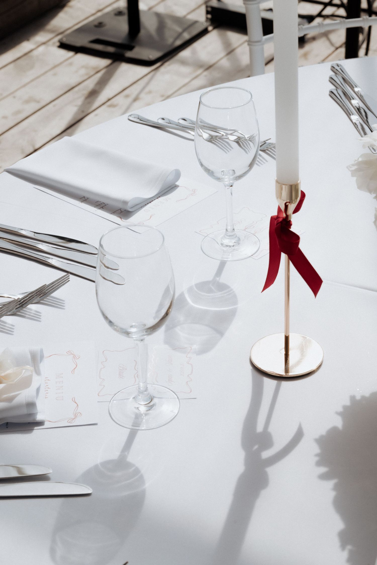 Overhead shot of a white wedding reception setup with the bride walking past in red heels, captured in a modern coastal venue called Kupolas