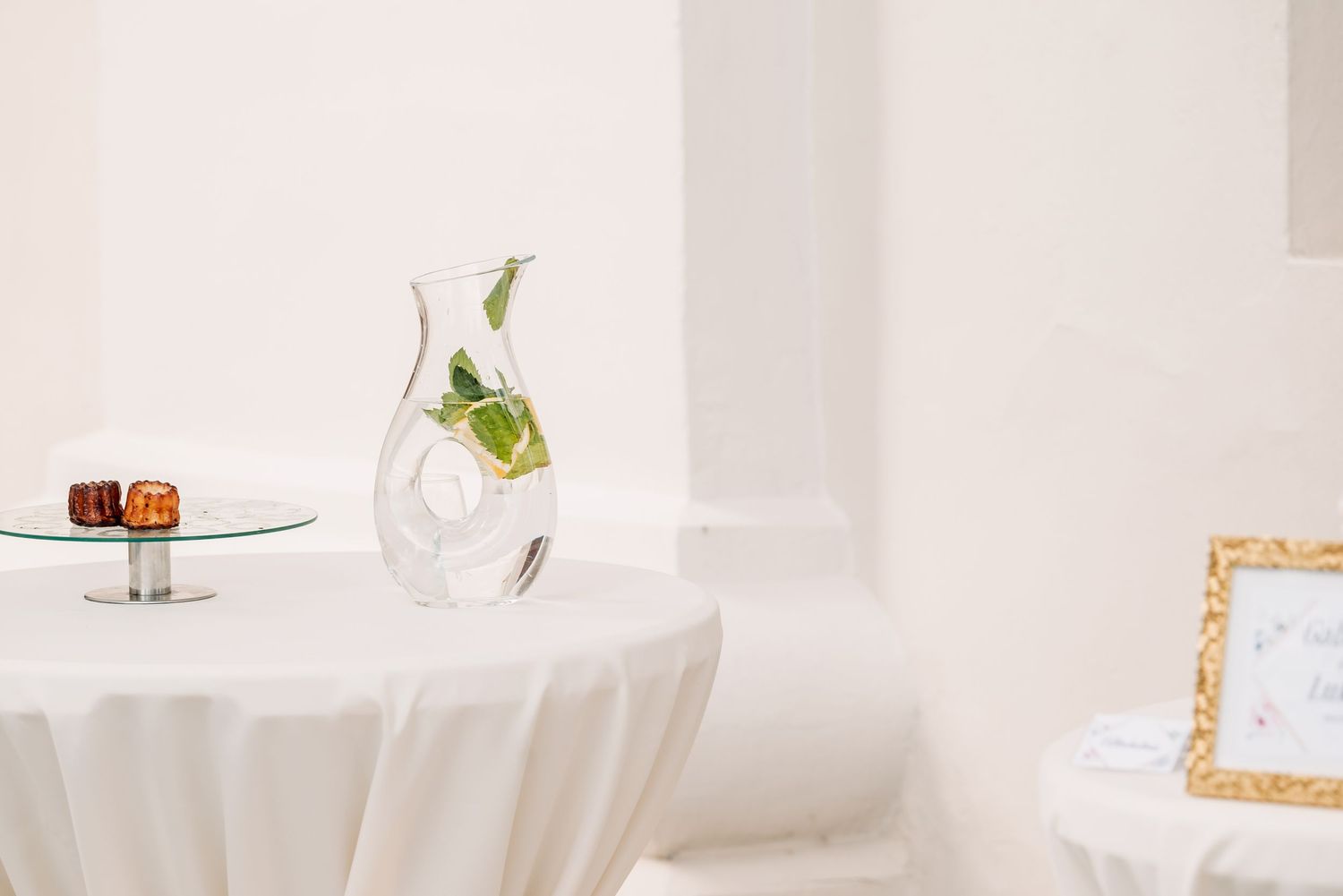Minimalist wedding decor setup with a small round table, single flower in a vase, and natural light pouring in.