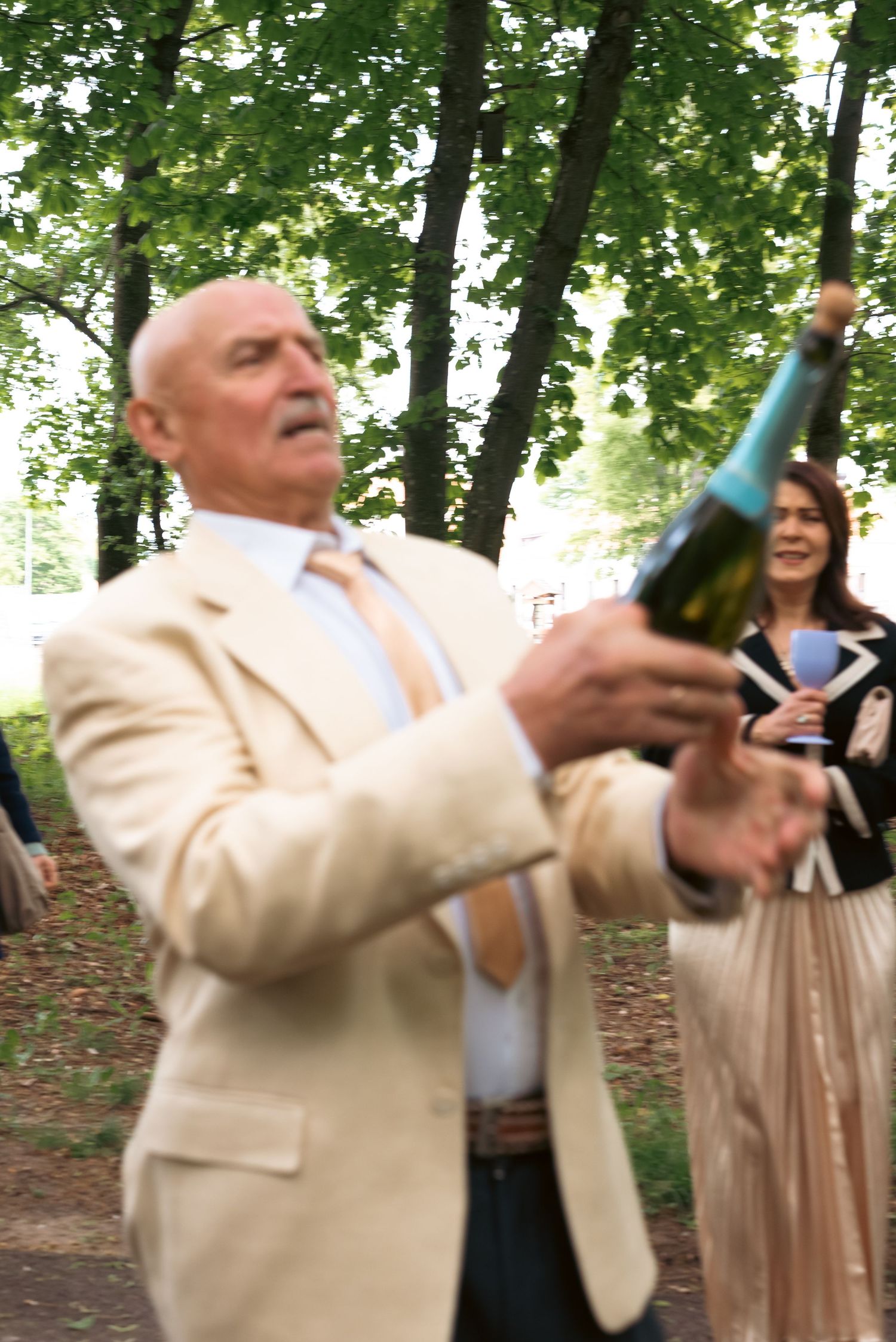 Father of the bride raising a toast outdoors, captured during a joyful moment in the wedding celebration.