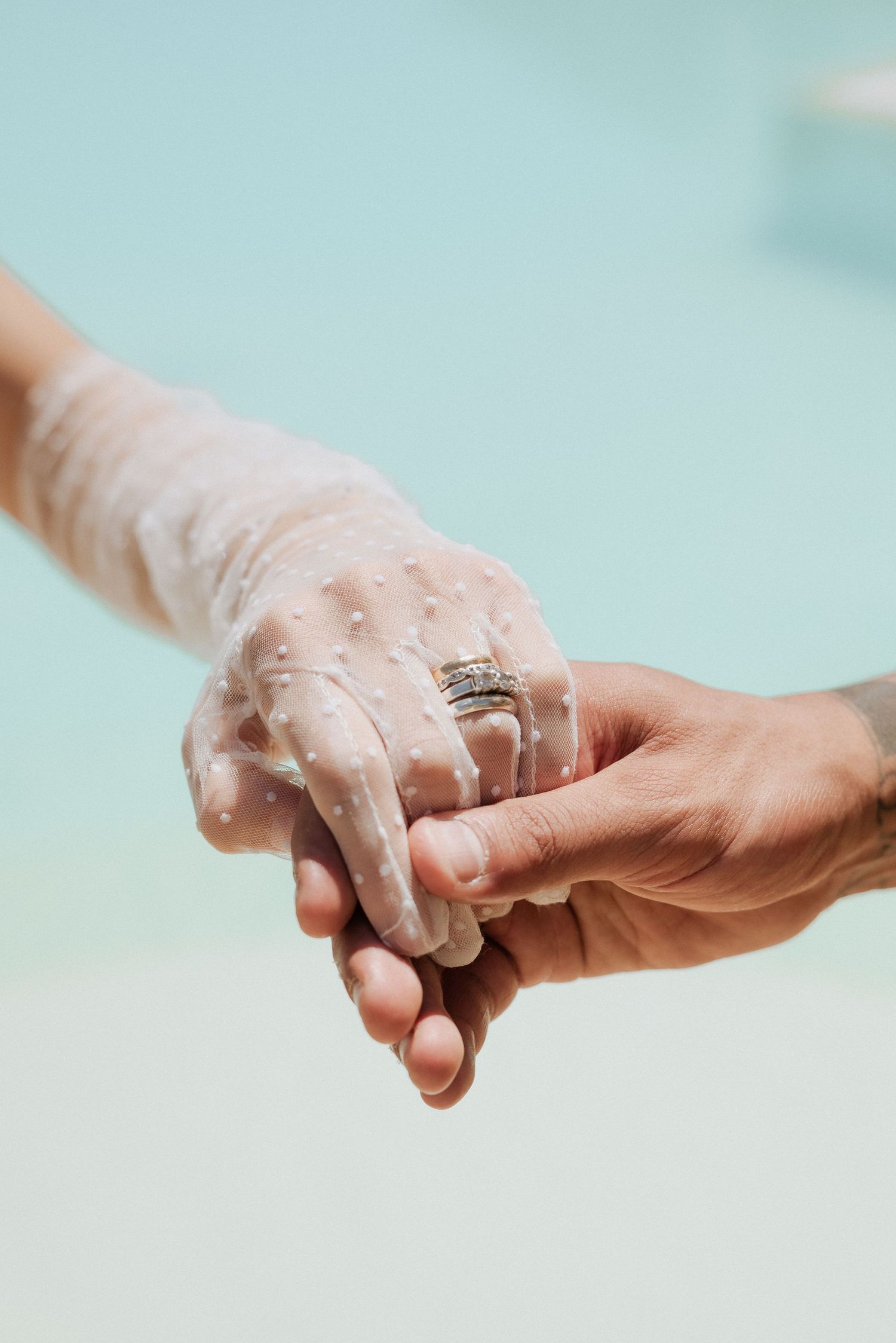 Close-up of the bride and groom holding hands over the pool, water reflecting their connection.