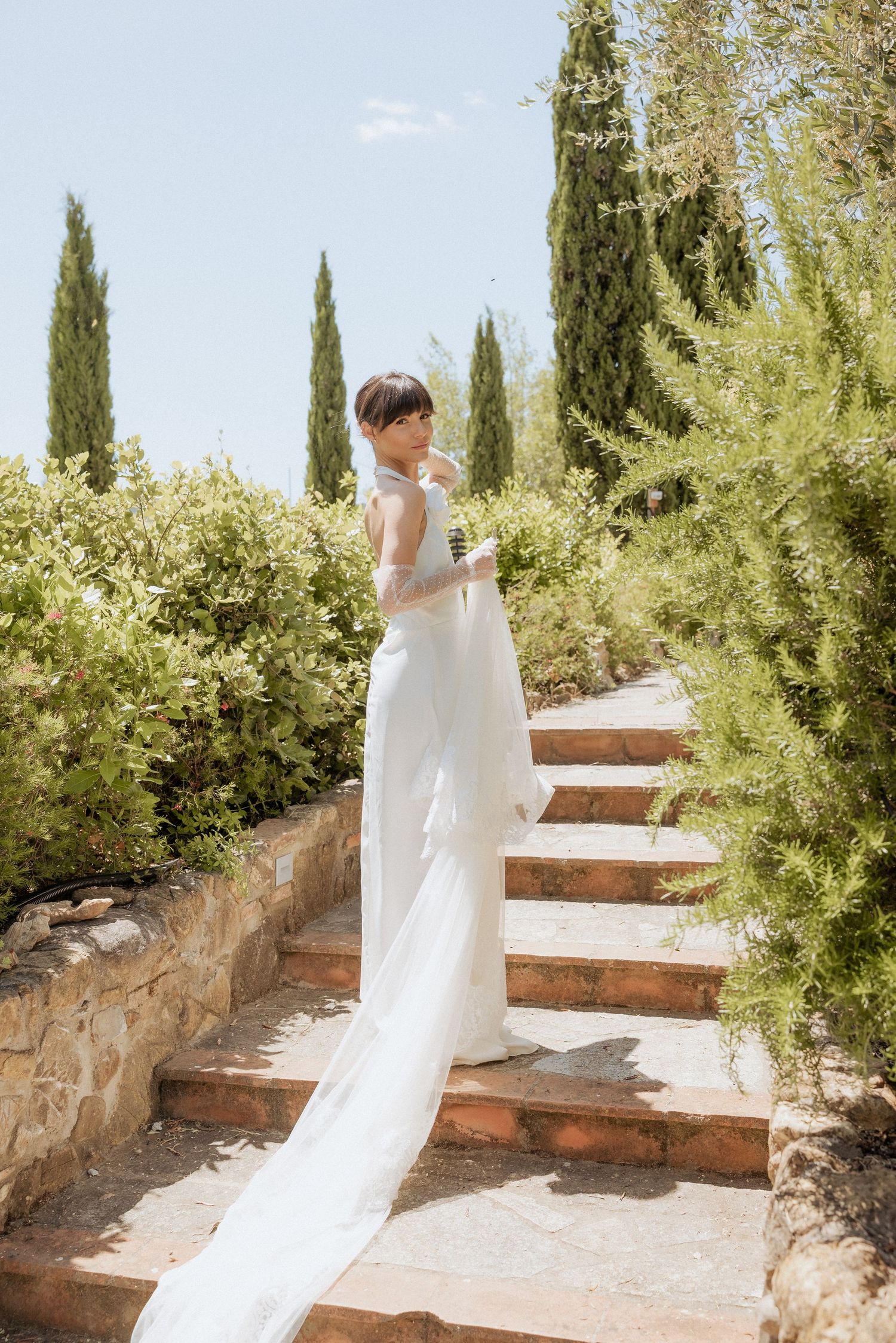 Bride walking away down a tree-lined Tuscan road, framed by iconic cypress trees and golden light.