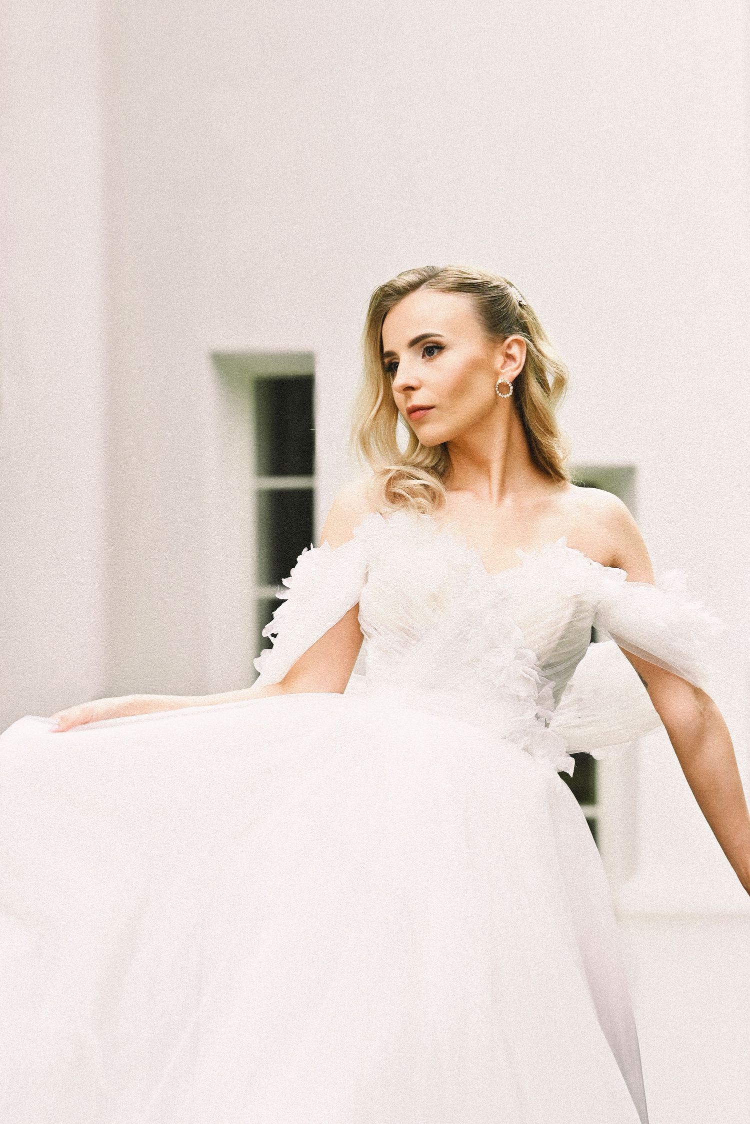 Bride standins outdoors in a modern white dress, captured mid-step in an elegant bridal portrait.