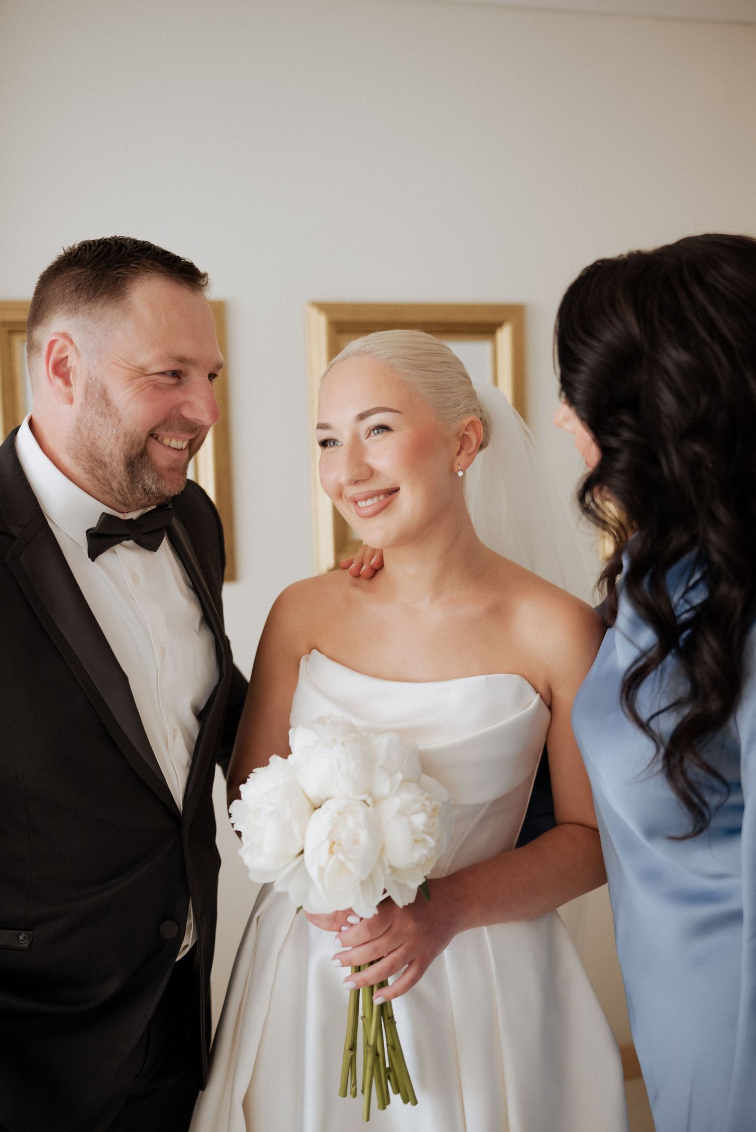 Parents sharing a joyful glance during their indoor wedding celebration, dressed in classic formal attire.
