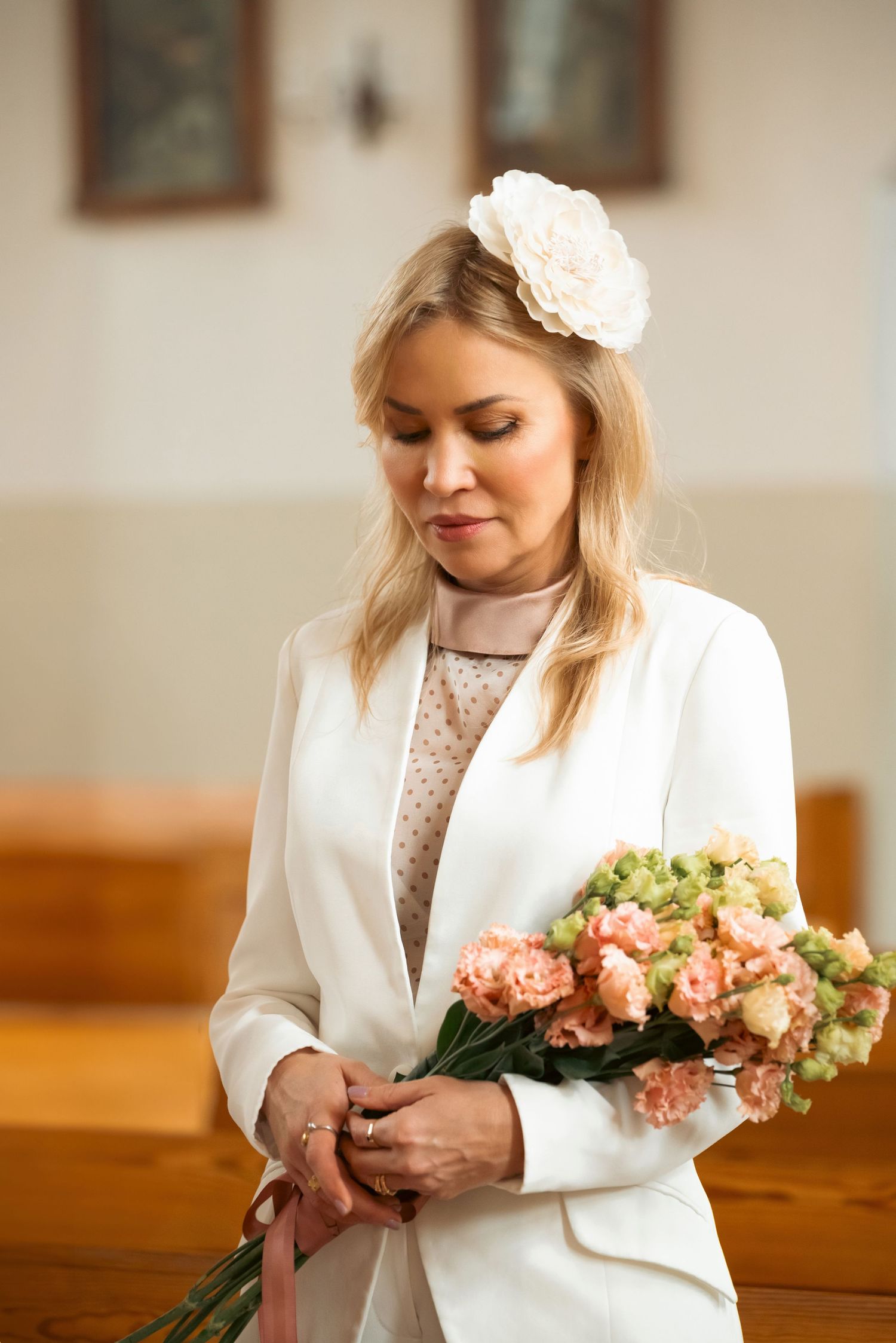 Bride holding a bouquet in her robe, smiling softly before getting into her wedding dress.