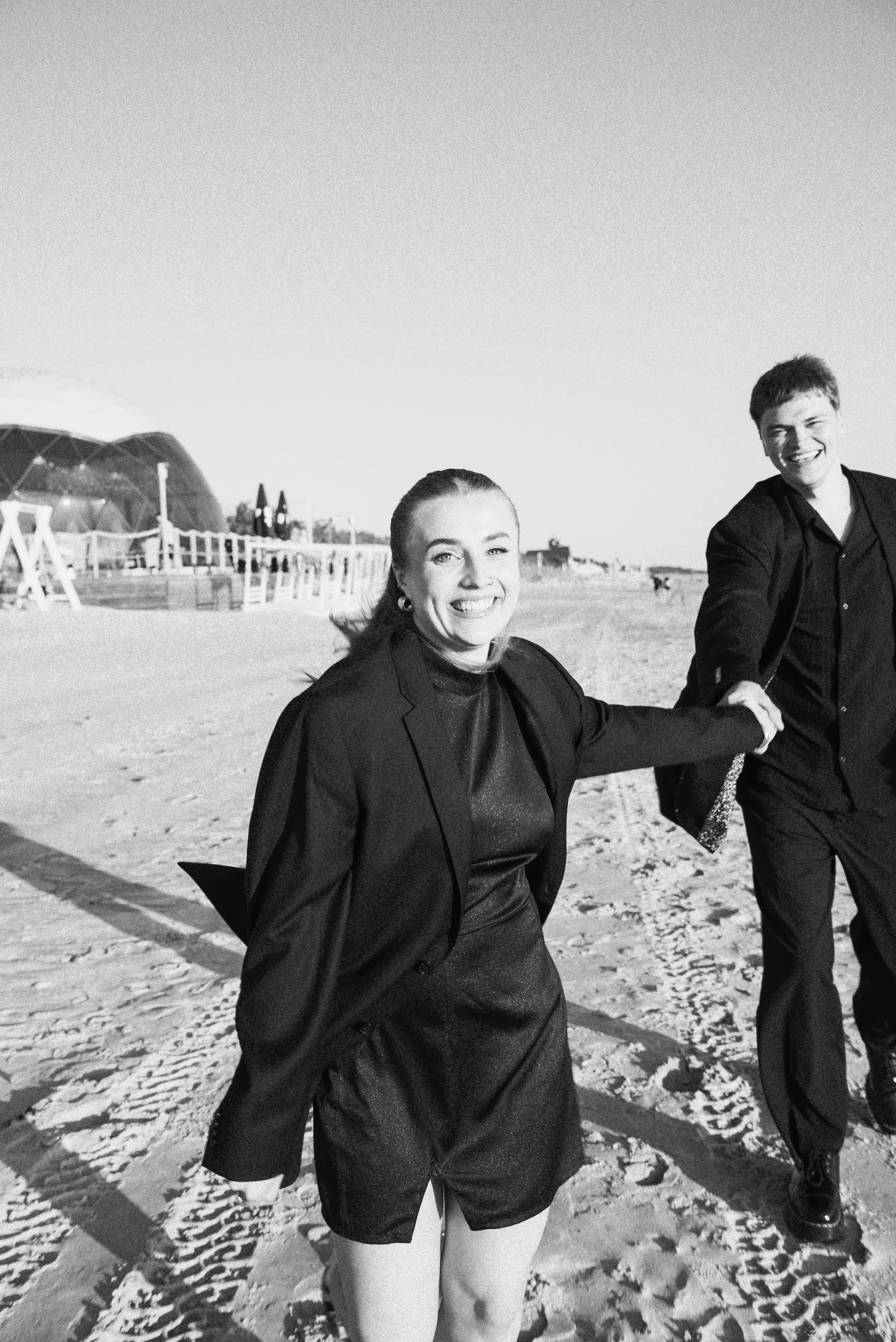 Black and white editorial-style portrait of the wedding guests walking near the coast in Klaipėda, Lithuania.