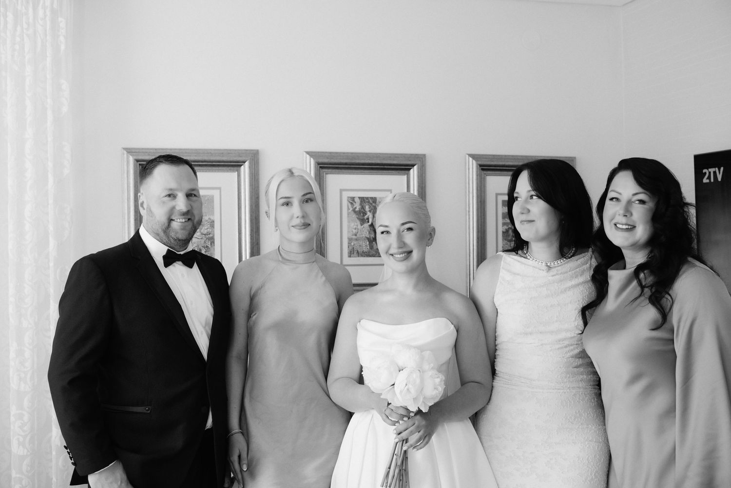 Timeless black and white family wedding portrait with bride, groom, and loved ones posed in a formal indoor setting.