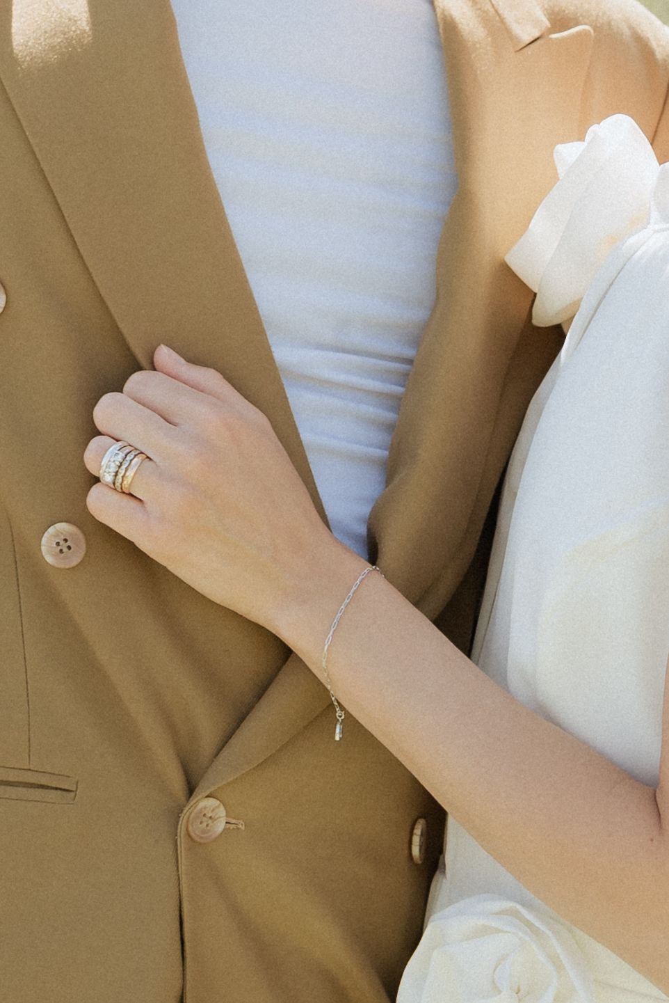 Close-up of bride’s hand resting on the groom’s chest, showcasing her engagement ring and soft dress details.