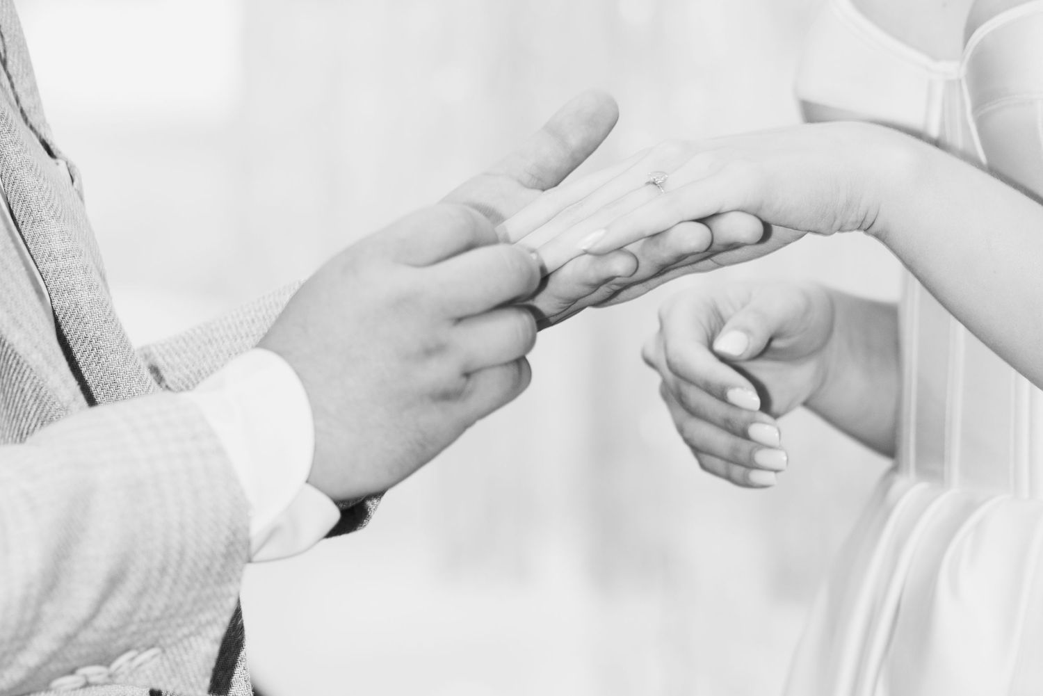 detalė iš arti, kuomet jaunikis nuotakai mauna žiedą ceremonijos metu