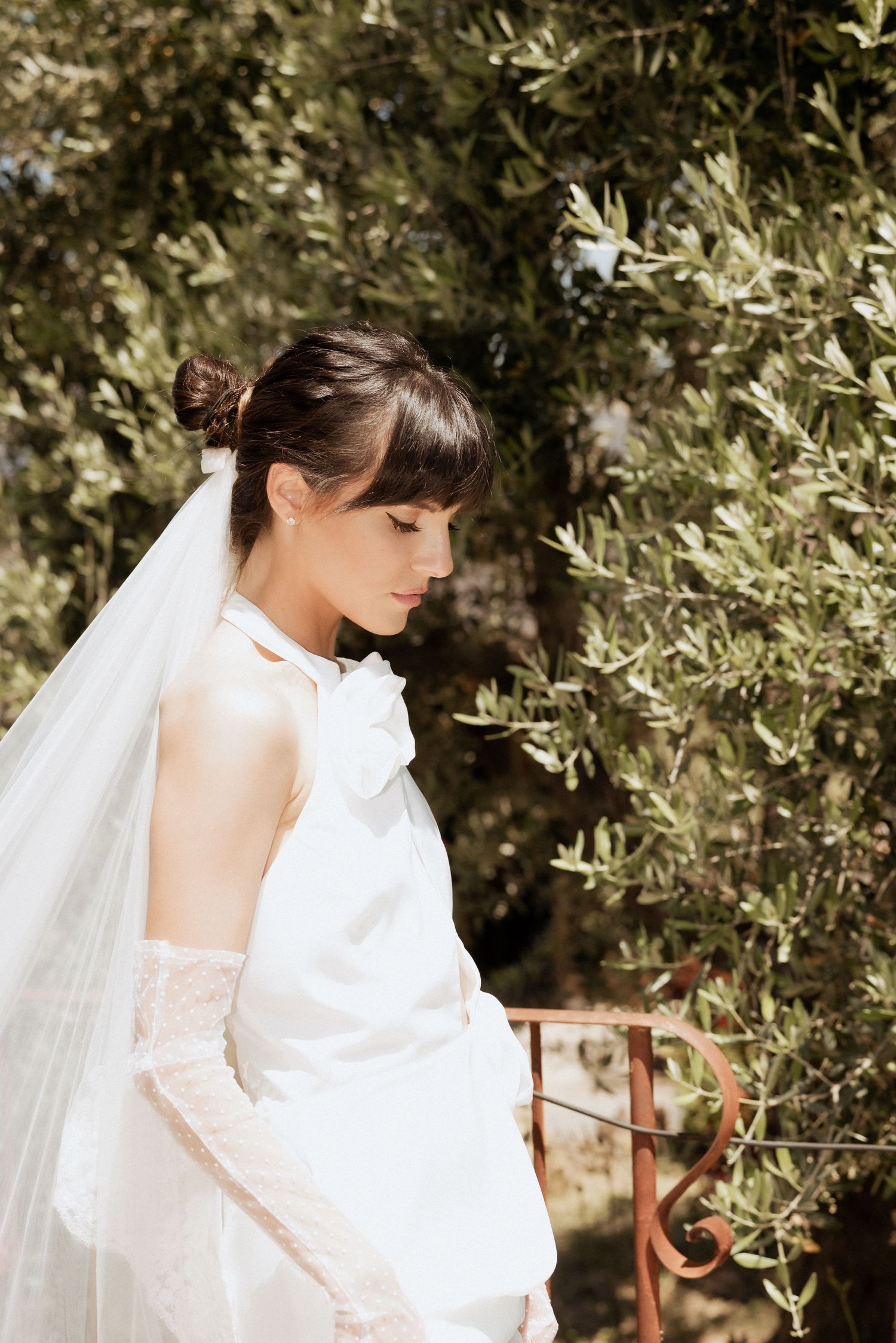 Bride smiling while walking through an olive grove in Tuscany, her veil gently flowing in the breeze.