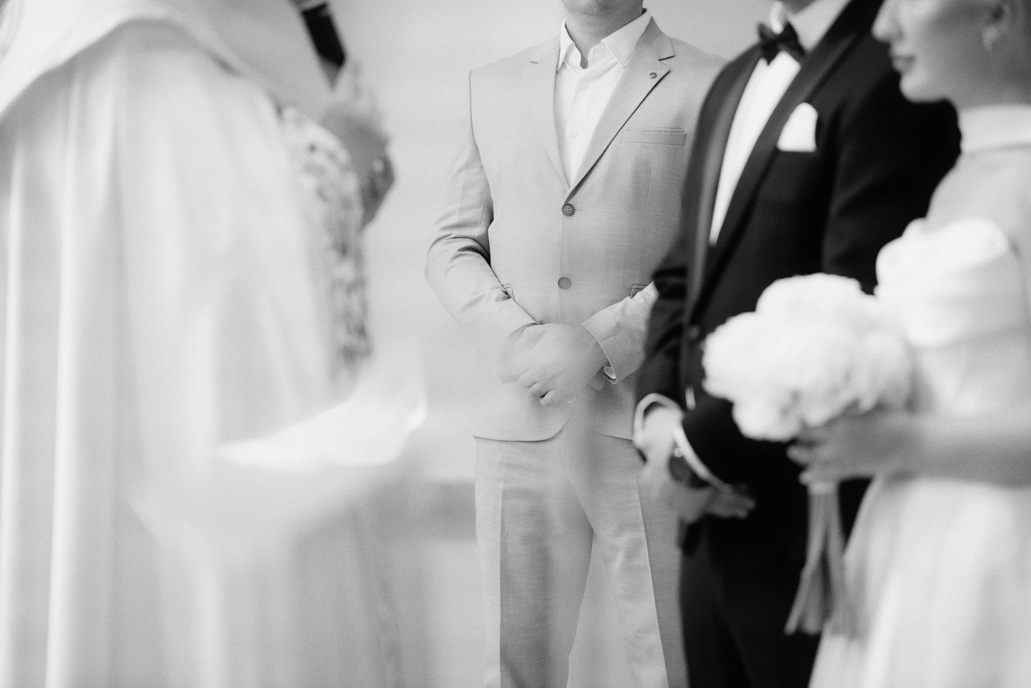 Black and white close-up of groom placing a ring on the bride’s finger during their wedding ceremony.
