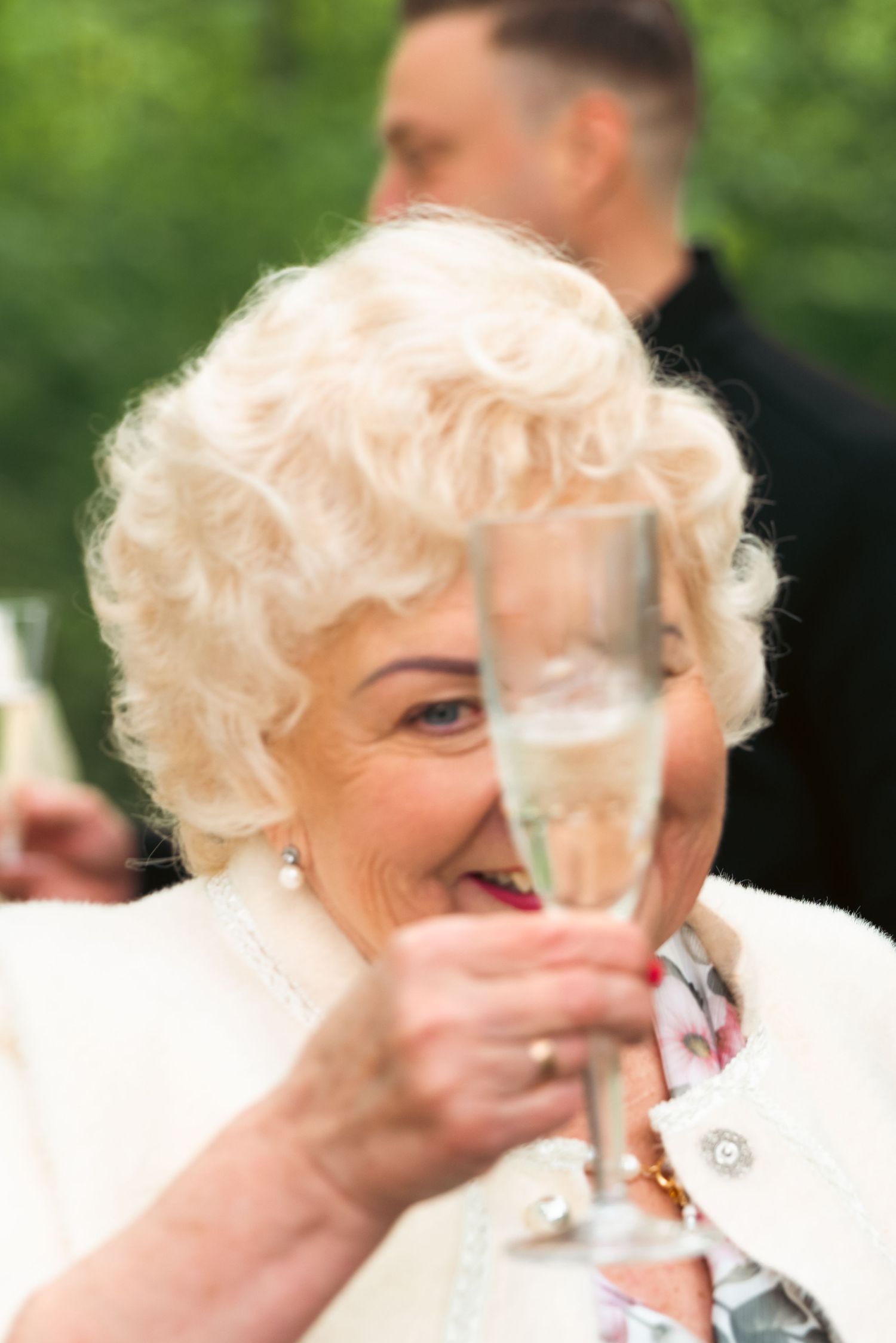 Close-up of a guest holding a glass of sparkling wine during the wedding reception toast.