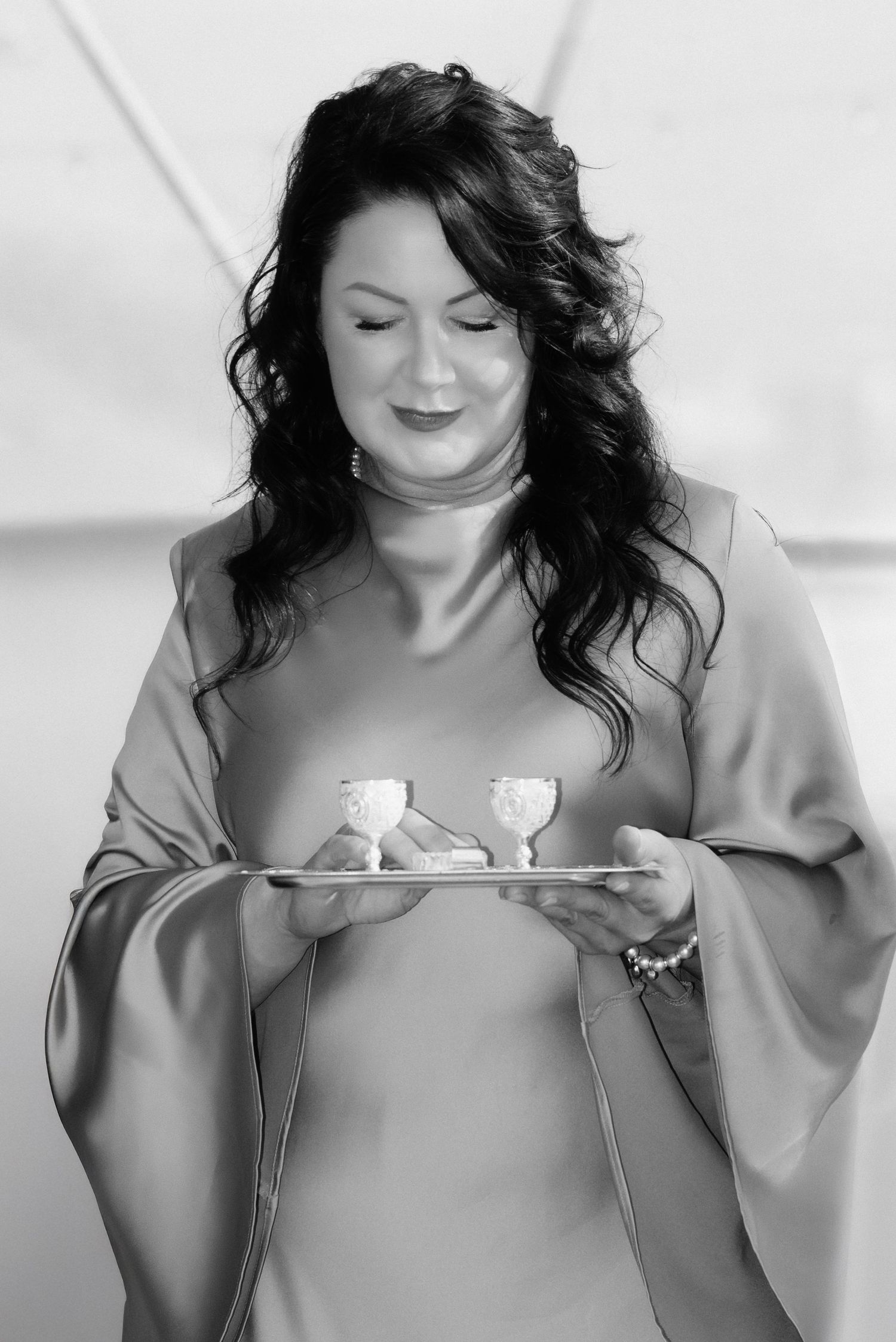 Elegant black and white portrait of the mother of the bride, smiling with grace in a soft off-shoulder gown on the wedding day.