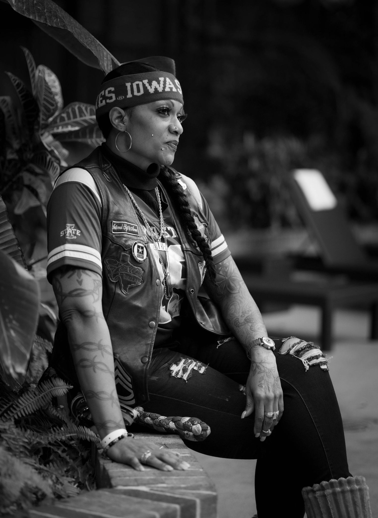 A cyclist wearing a bandana and tattooed arms rests on steps in black and white photography.